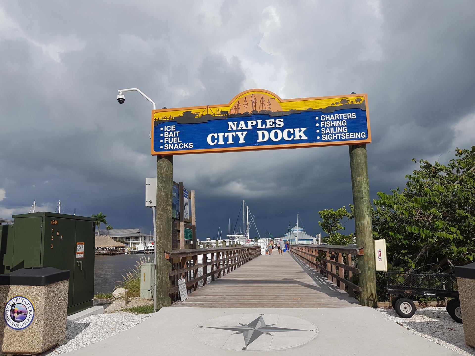 A large sign over a wooden walkway leading to a marina.