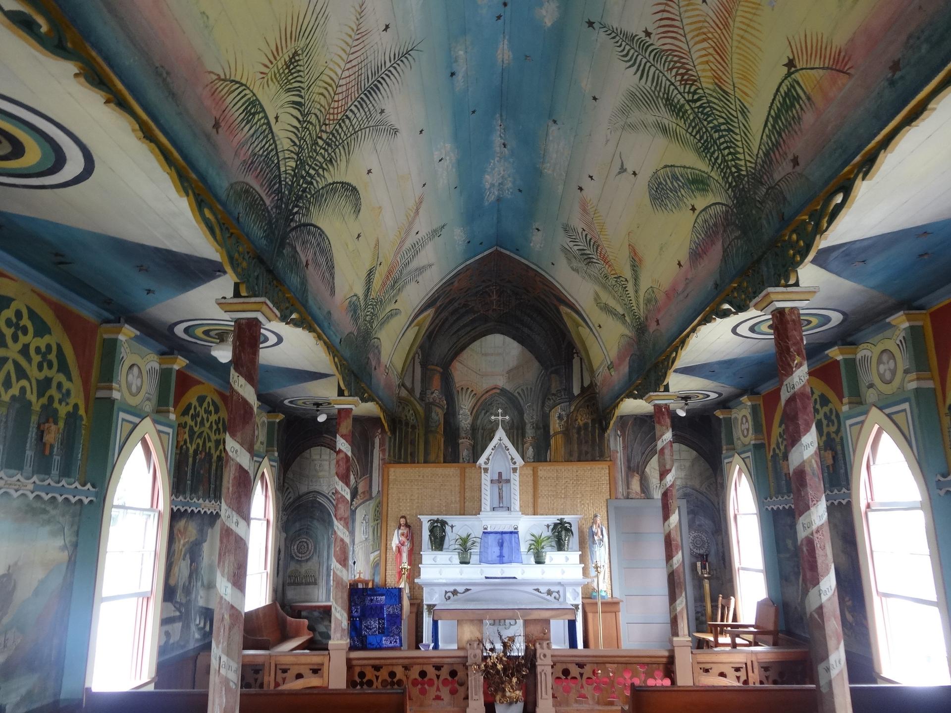 Ornate, colorful church interior with painted ceiling and altar, brightly lit.