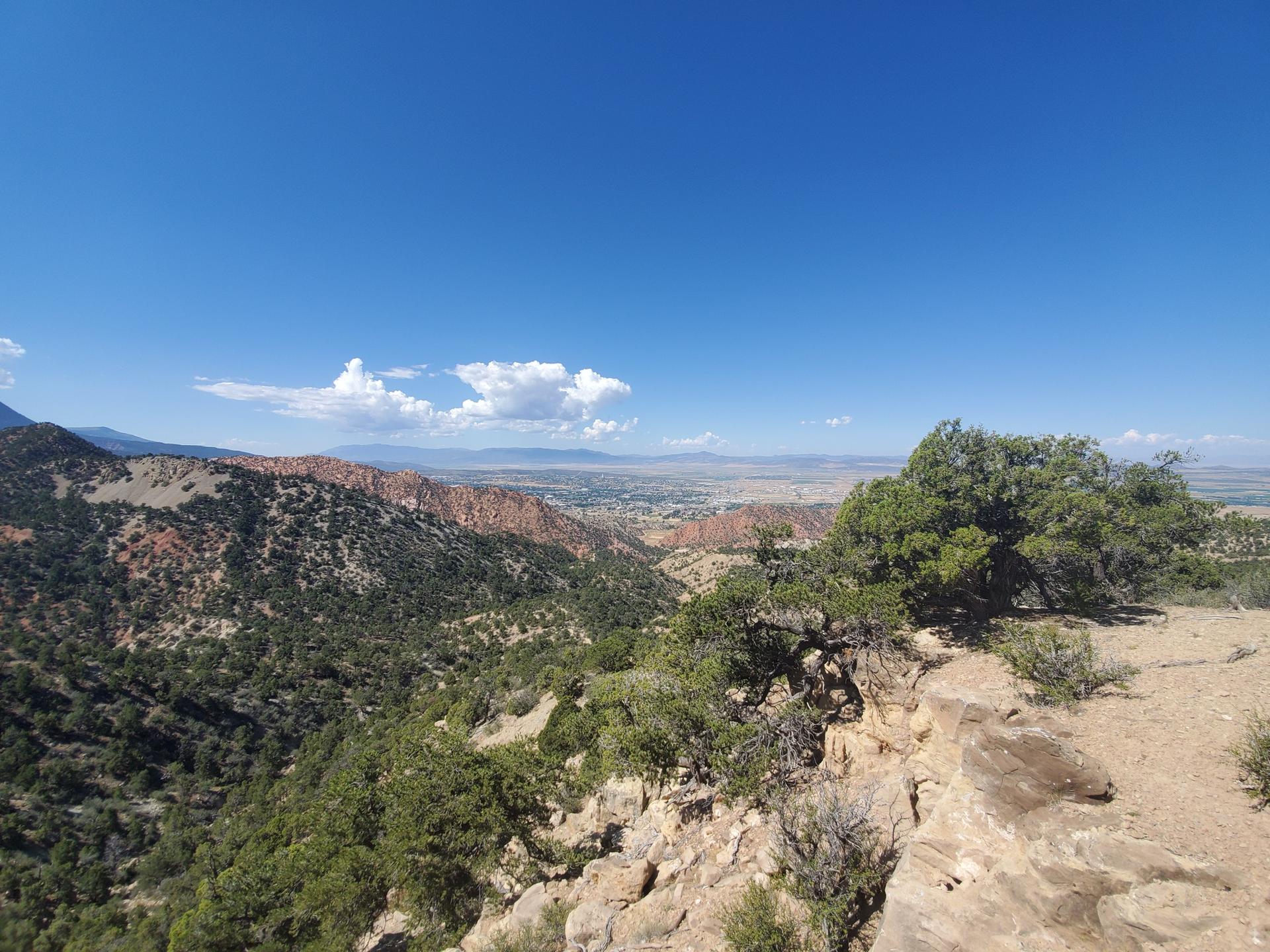 Panoramic view of a vast mountainous landscape under a clear blue sky with clouds.