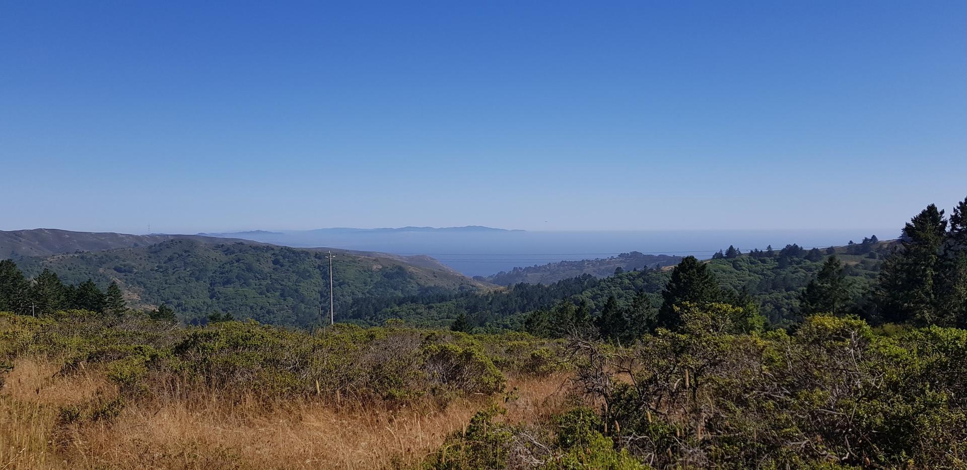 Panoramic view of green rolling hills extending to a hazy horizon.