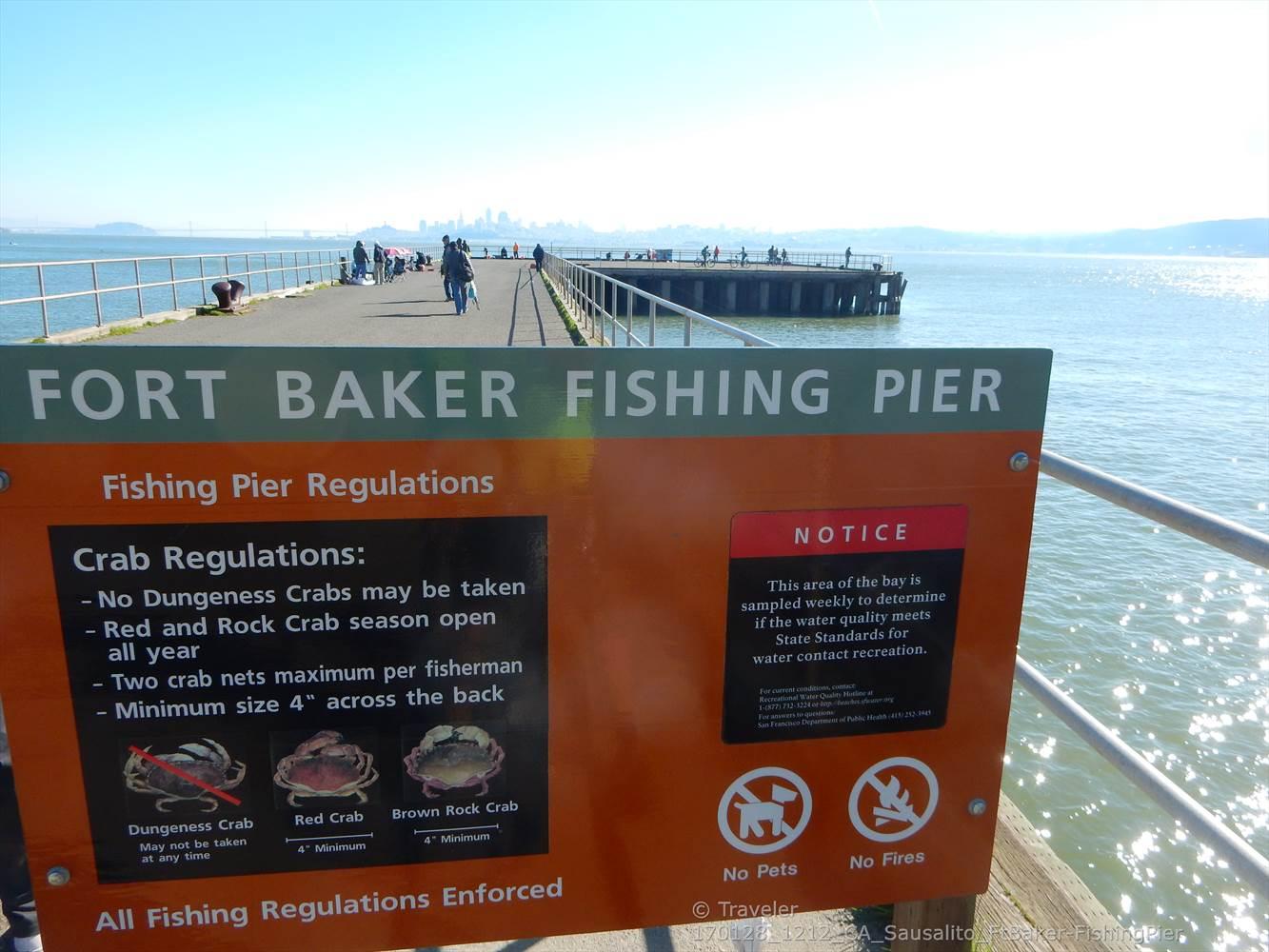 Orange sign with fishing regulations on a pier with people fishing.