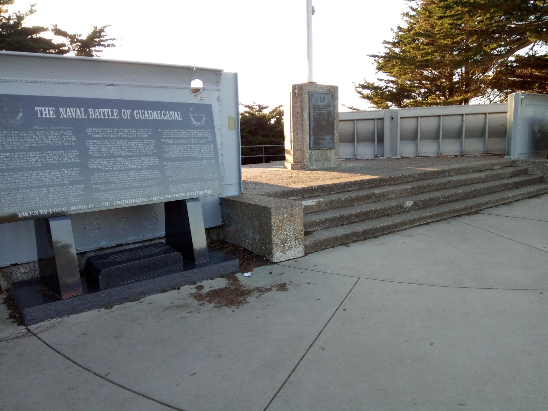 Outdoor memorial with large informational plaques and concrete steps, sunny.