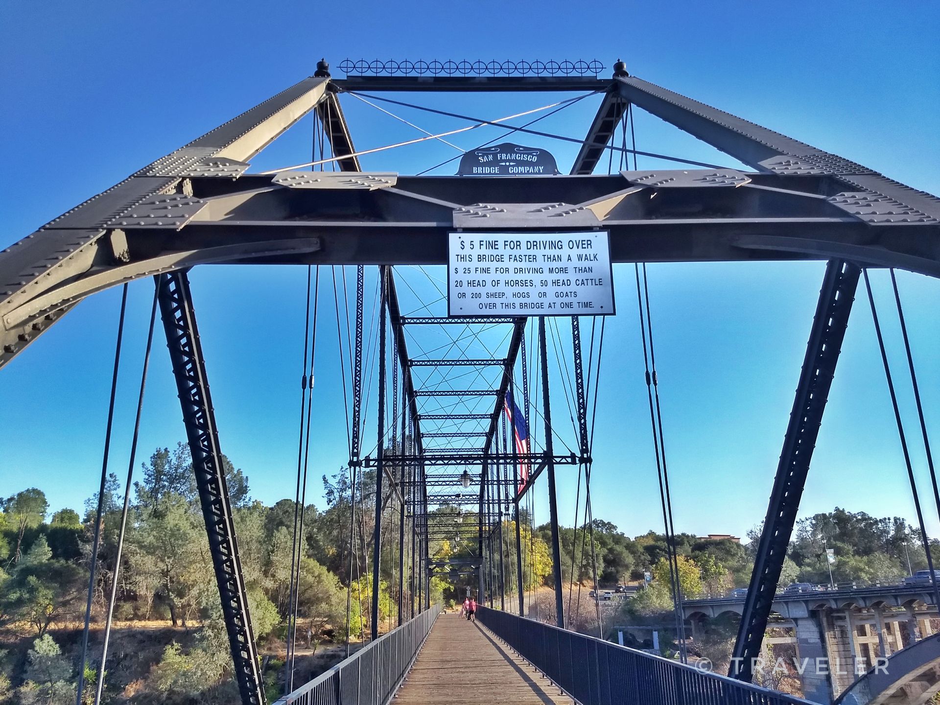A historic metal truss bridge with a sign, viewed from below on a sunny day. - Lake Natoma – Folsom Historic Truss Bridge loop from Iron Point