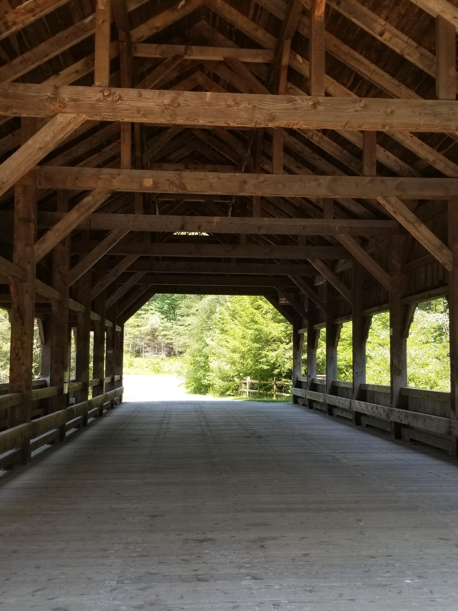 Inside a rustic wooden covered bridge, light visible at the far end.