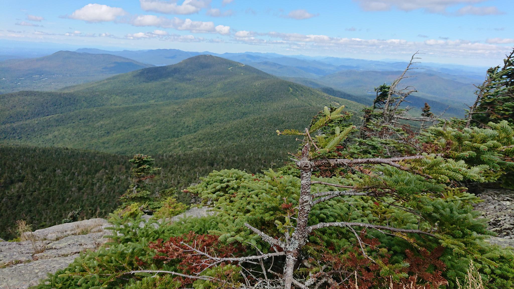 Panoramic view of green mountains under a bright blue sky.