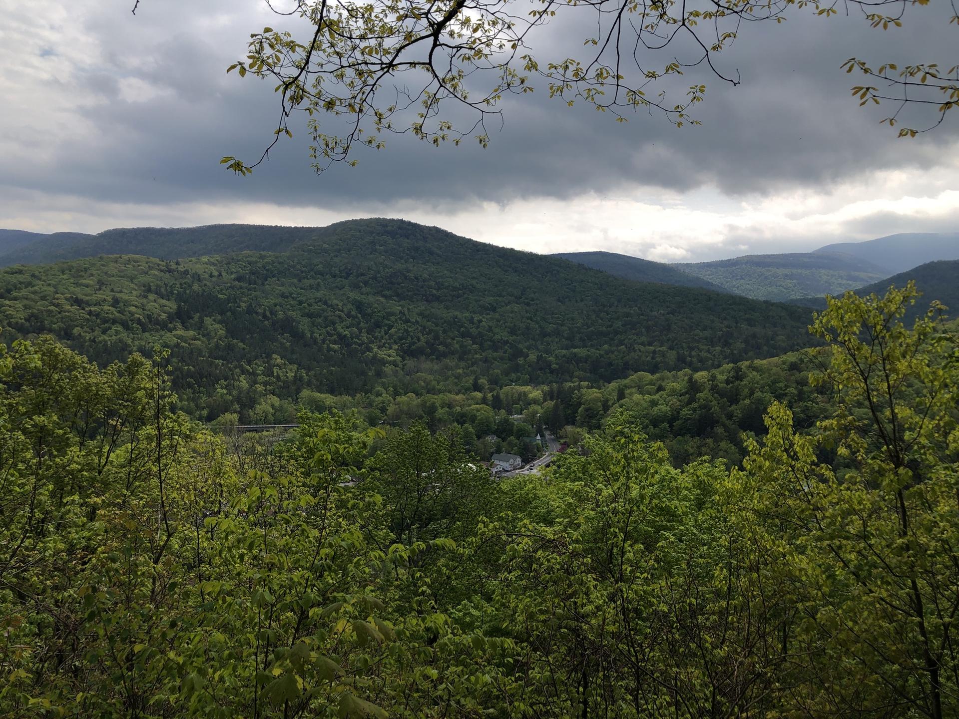 Dense green mountains under a dramatic cloudy sky, with a valley visible.
