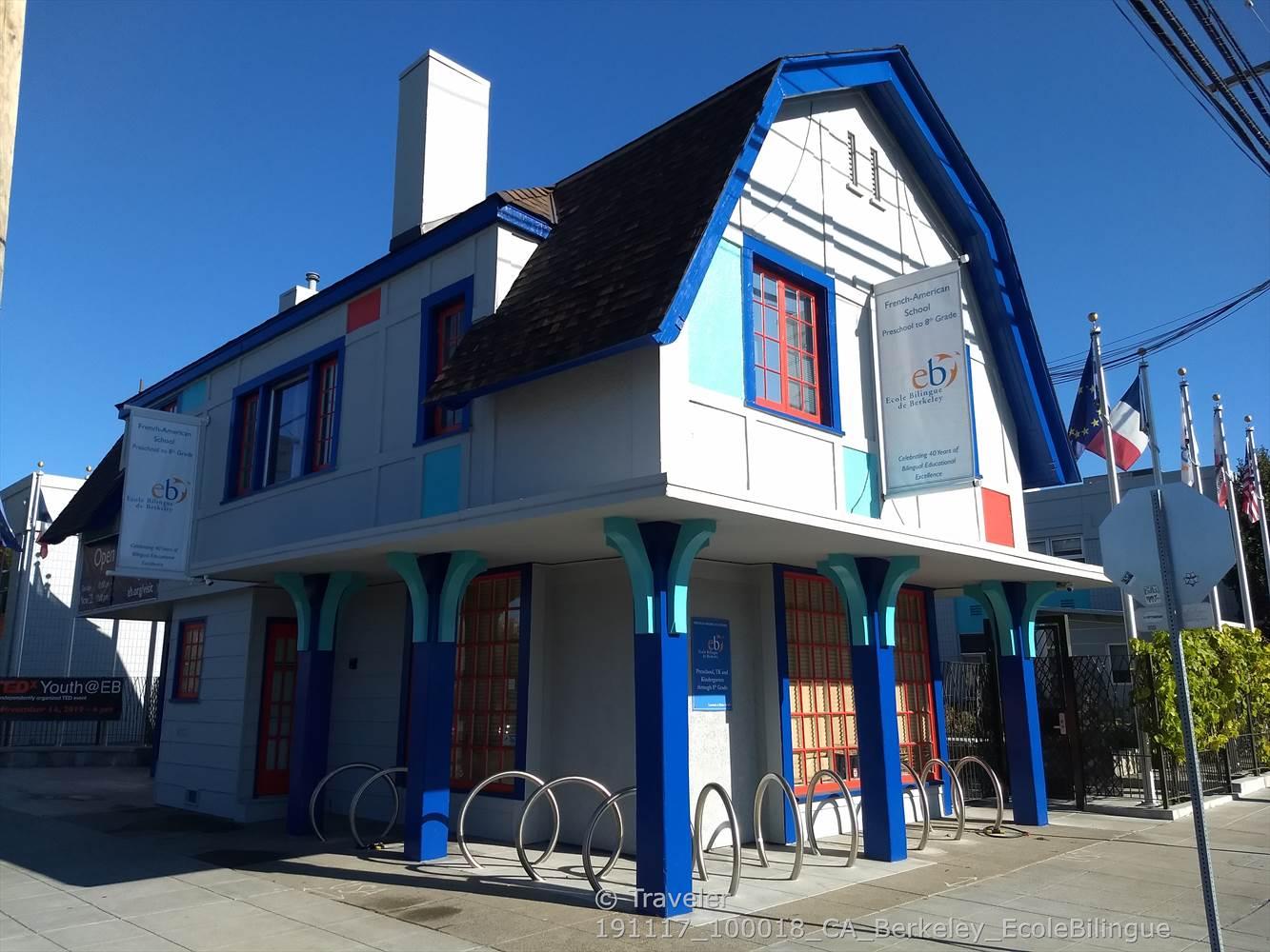 Brightly painted building with blue columns and bike racks under a clear sky.