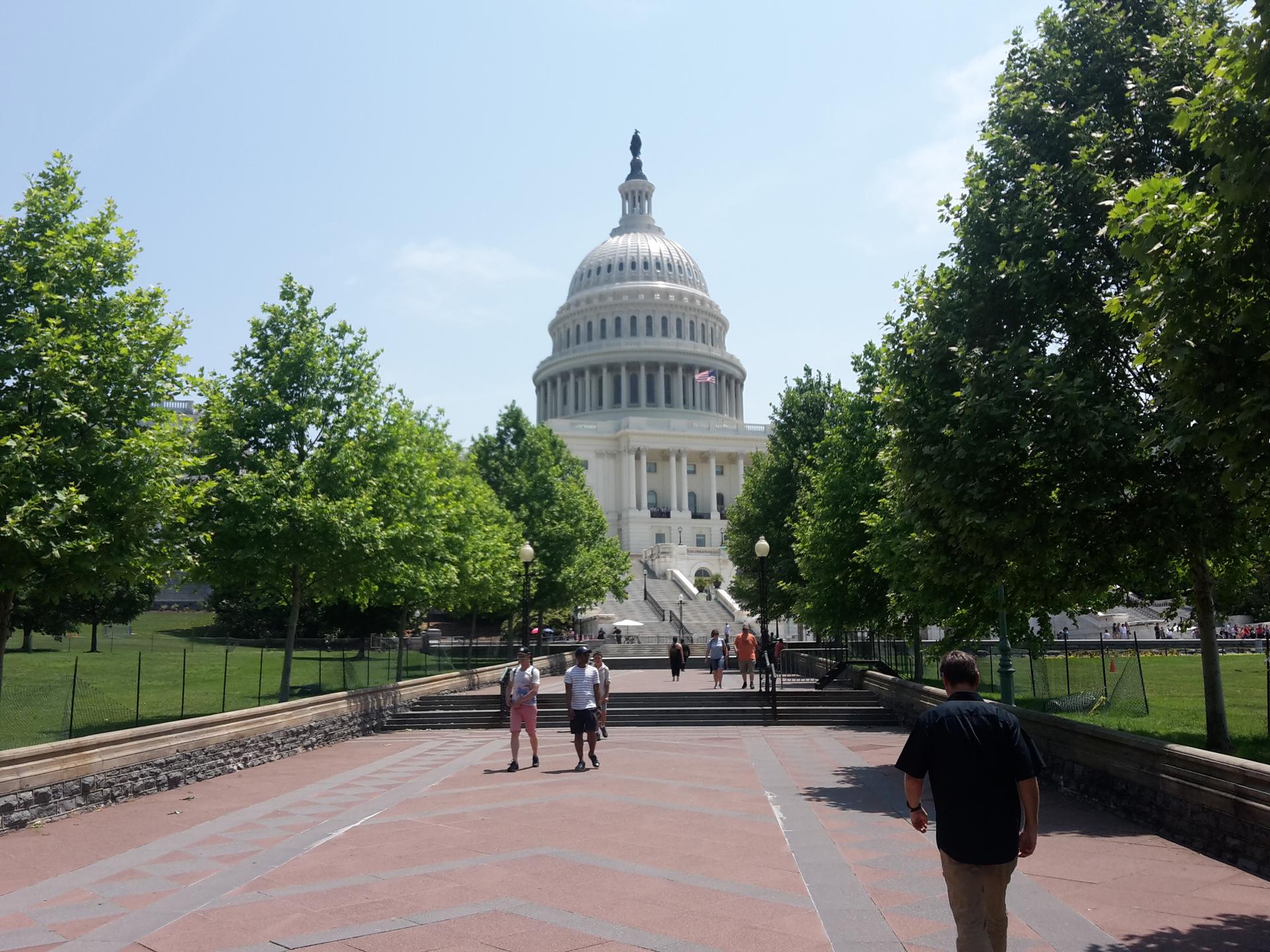 Large domed building with columns, people walking on a sunny day.