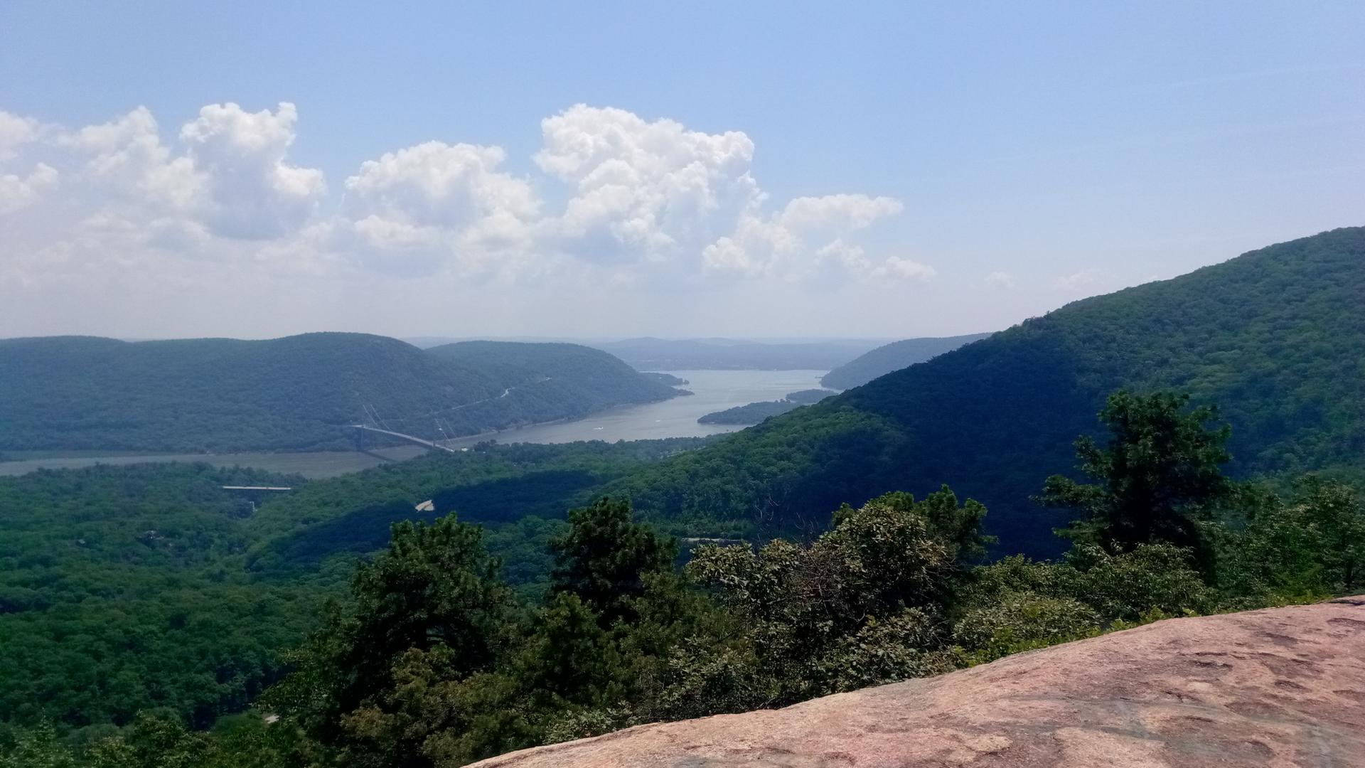 Panoramic view of a wide river winding through green, forested mountains.