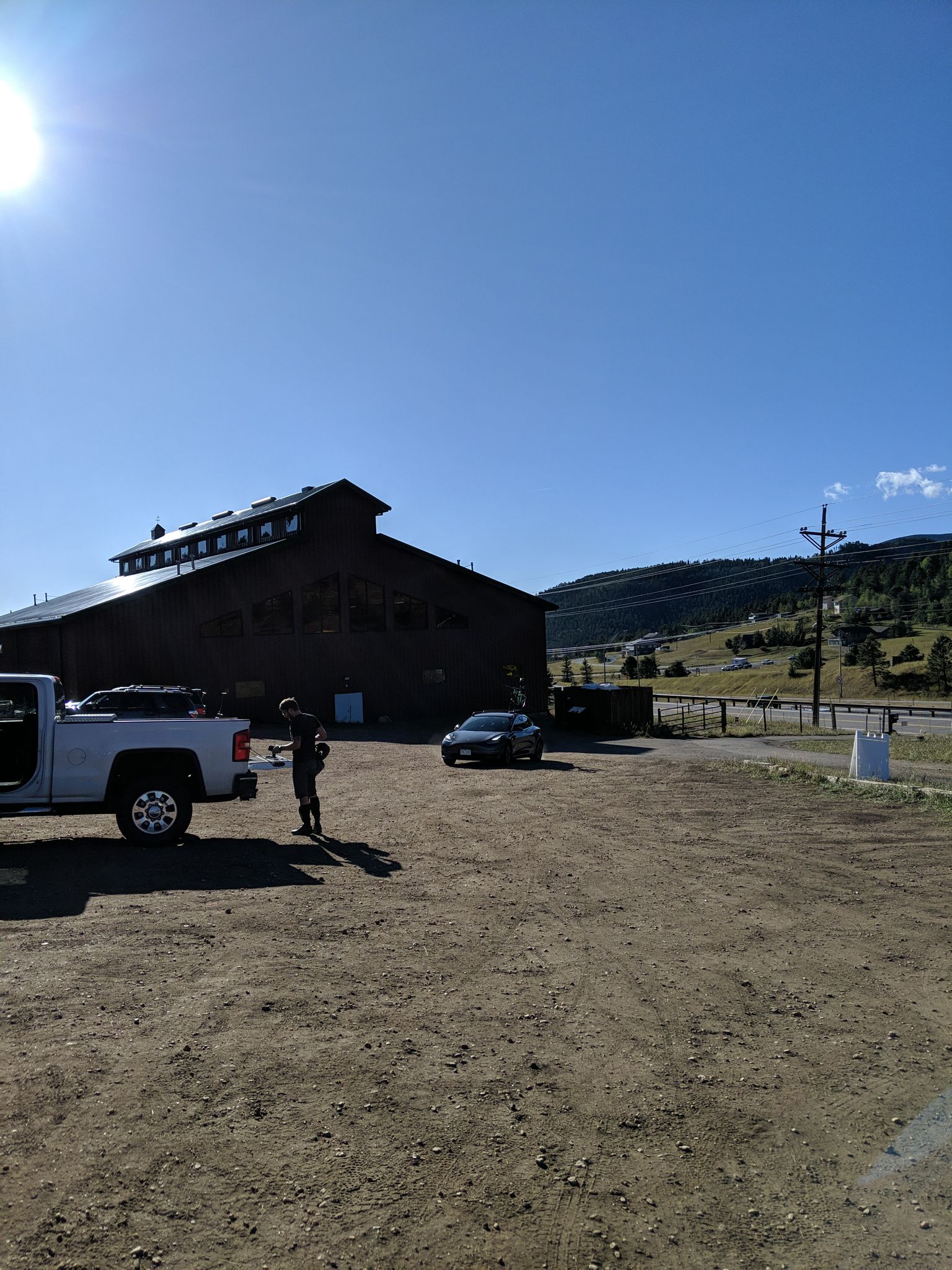 A person stands near a white truck in a sunny dirt lot. - Portal and Outer Loop