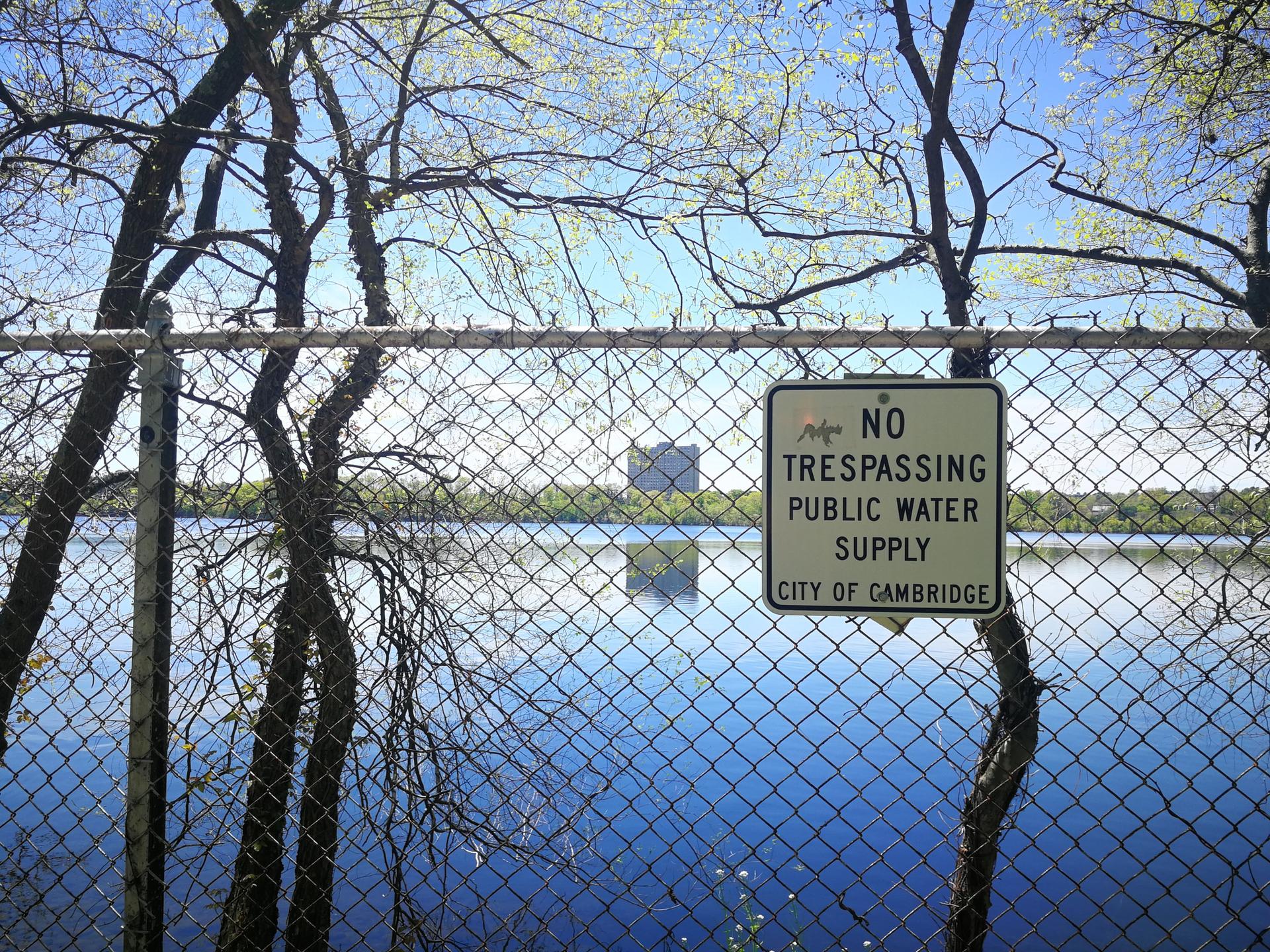 A "No Trespassing" sign on a fence overlooking a body of water.