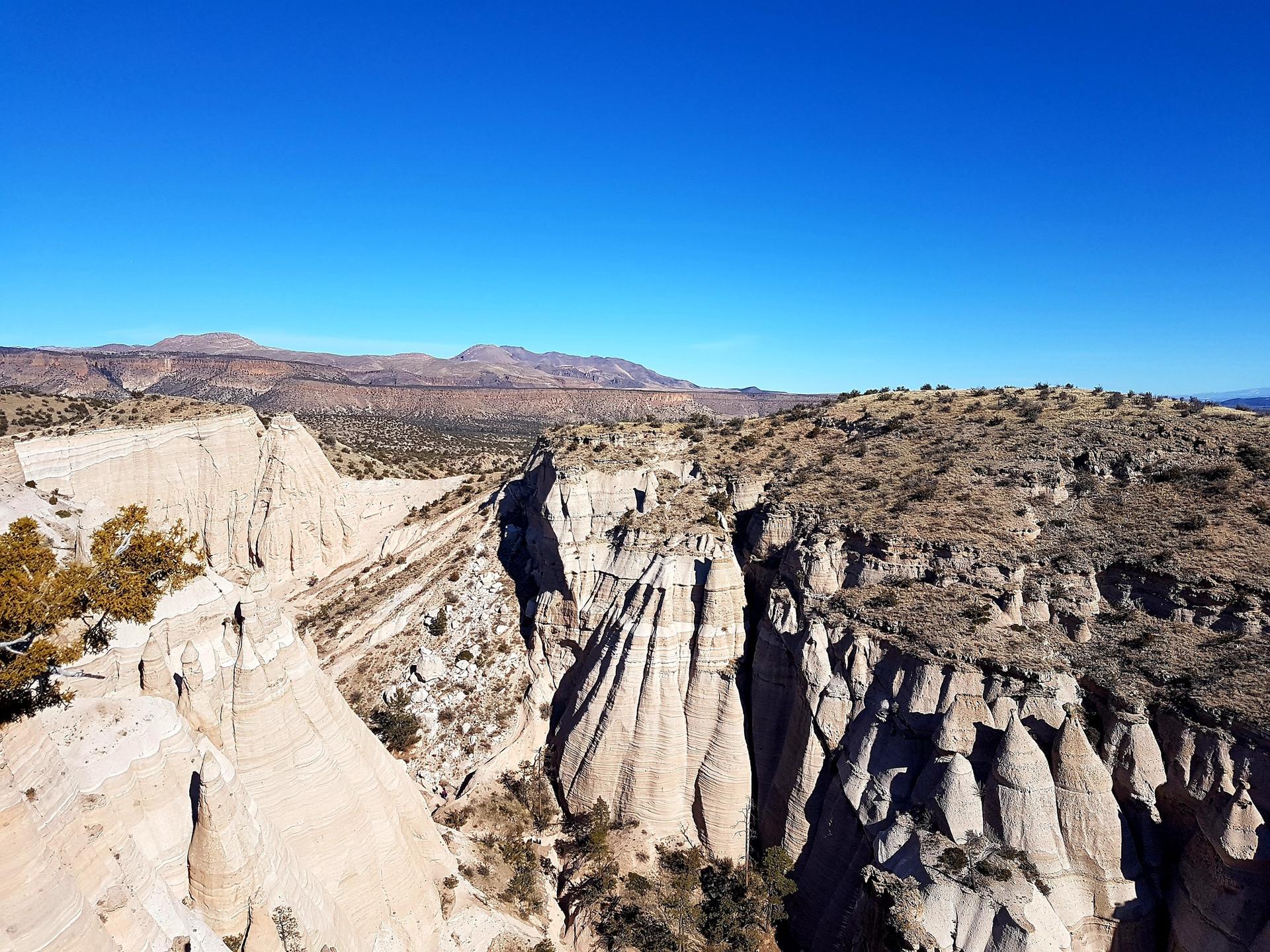 Expansive desert landscape with deep canyons, layered rock formations, and distant mountains.