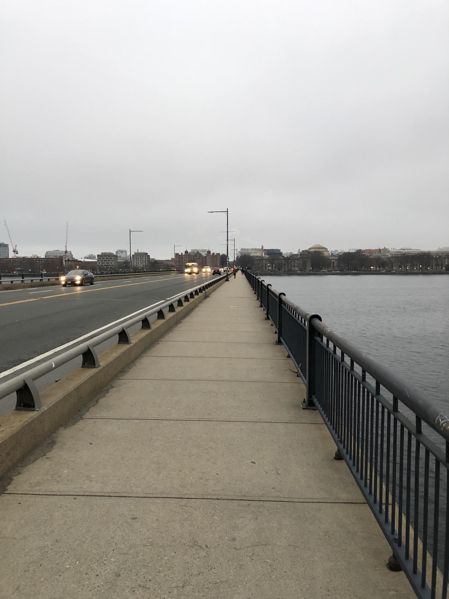 Pedestrian walkway and road on a bridge over water on an overcast day.