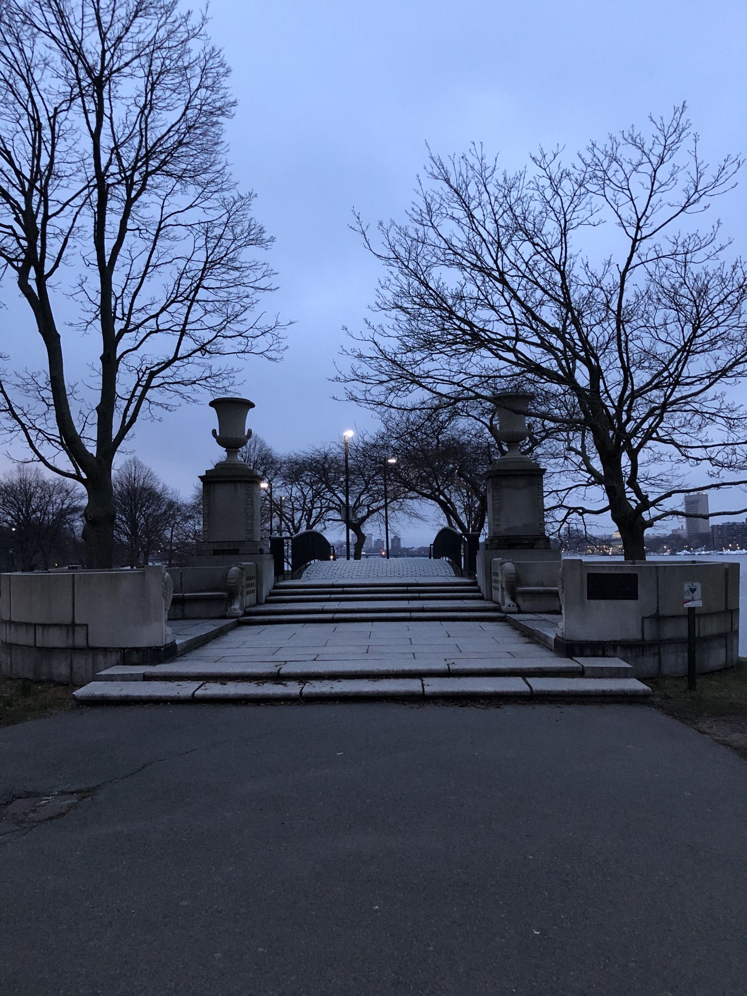 A grand stone staircase with urns leads up, framed by bare trees under a cloudy dusk sky. - Dr. Paul Dudley White Path