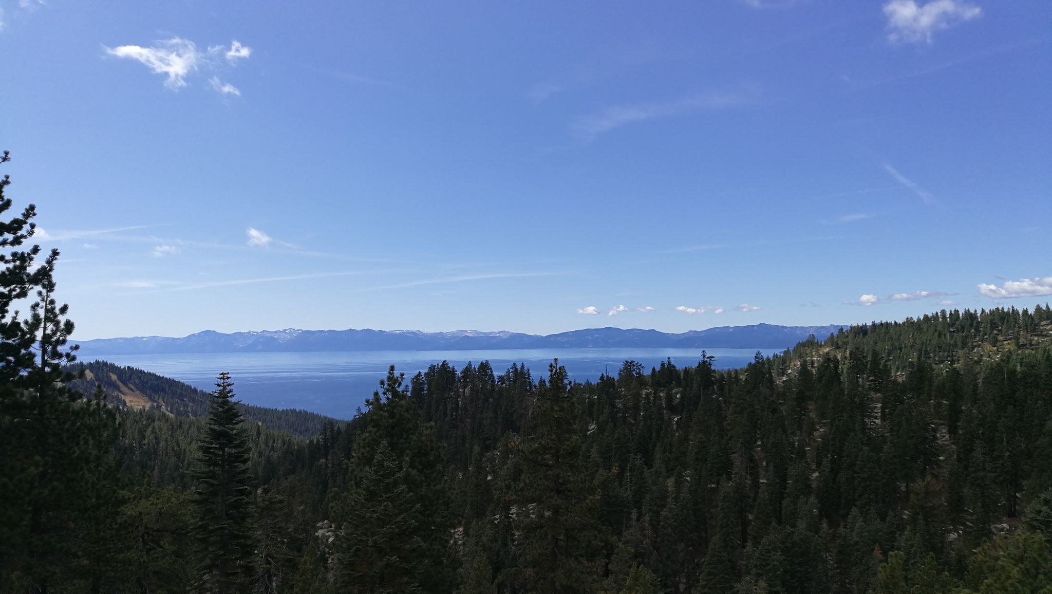 Wide view of a large blue lake framed by dense green forests and mountains. - Incline Flume Trail Trailhead – View of Lake Tahoe loop from Trippy Rock