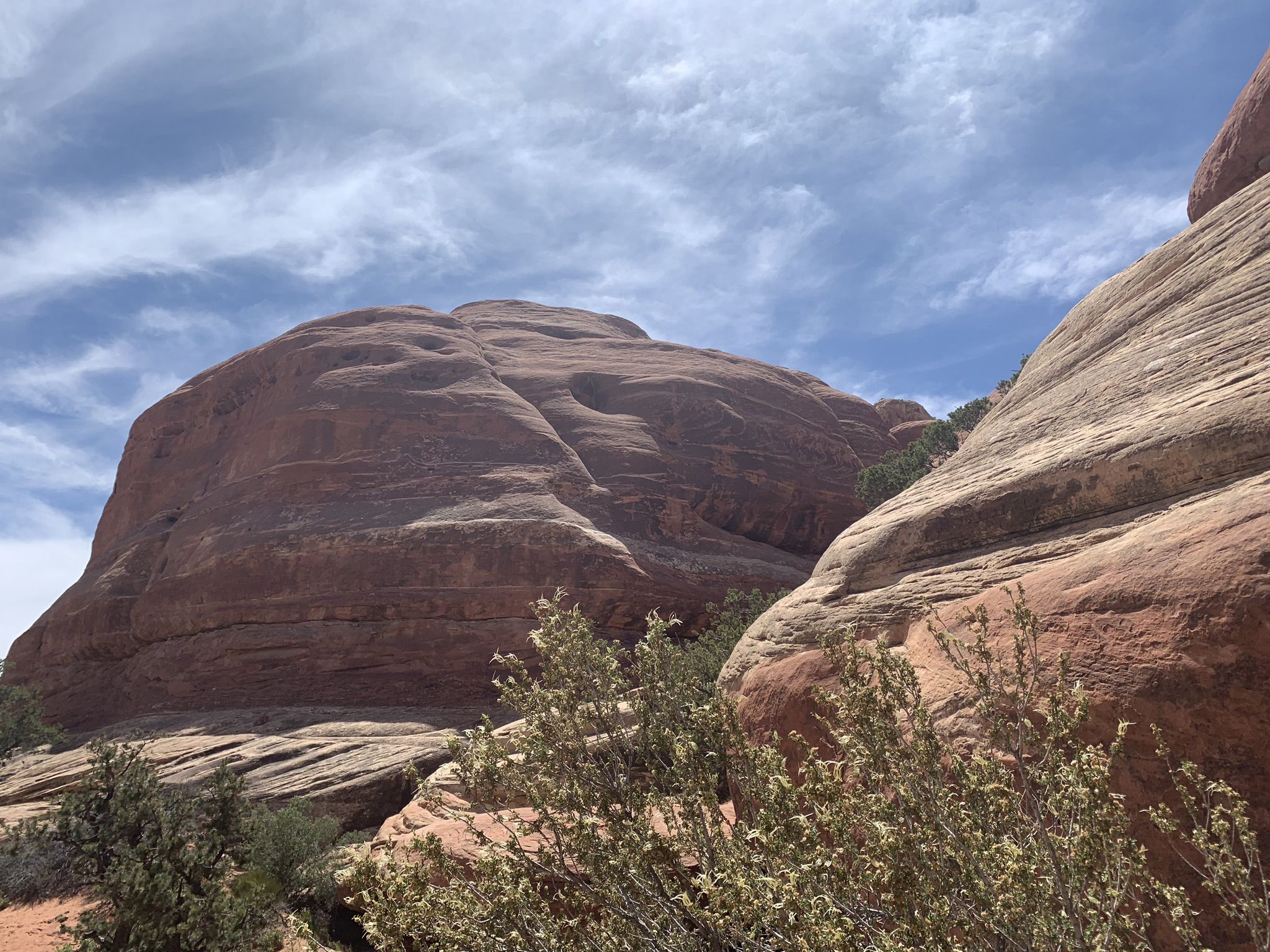 Large, layered red rock formations under a partly cloudy blue sky. - Elephant Hill – View over Chesler Park loop from Soda Spring