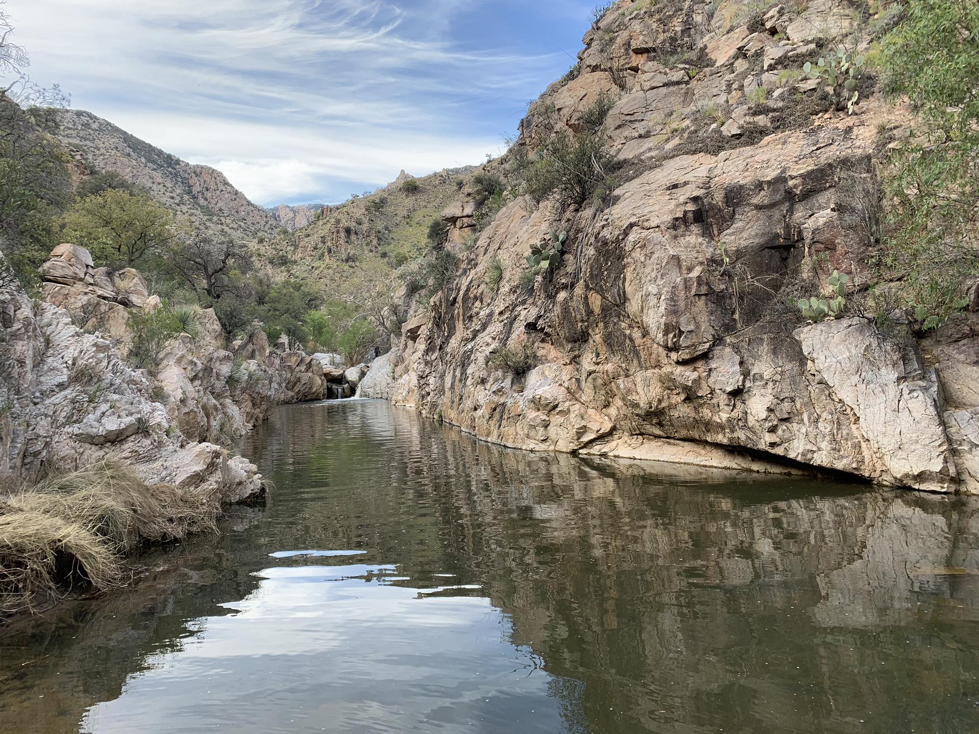 Calm river flowing through a narrow rocky canyon under a bright sky.