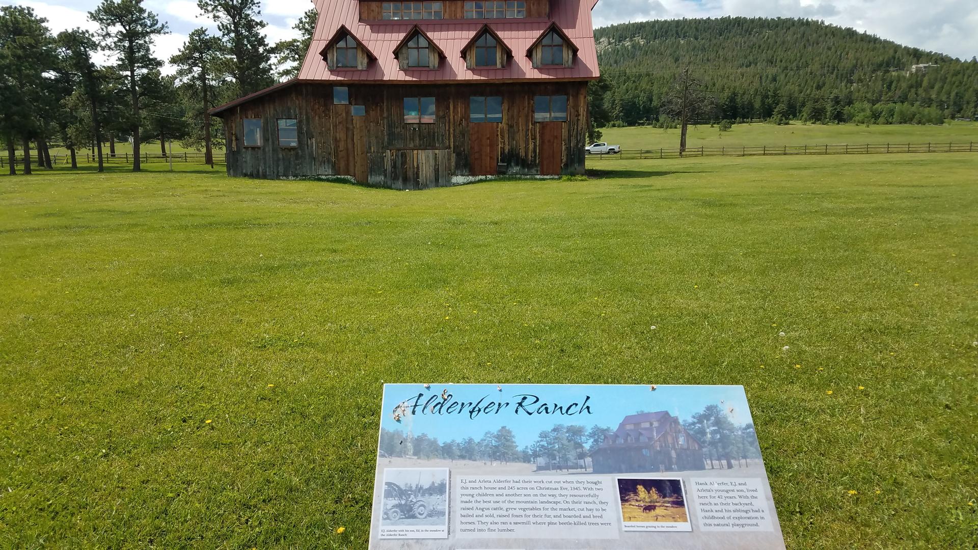 A wooden building in a green field with an information sign in front.