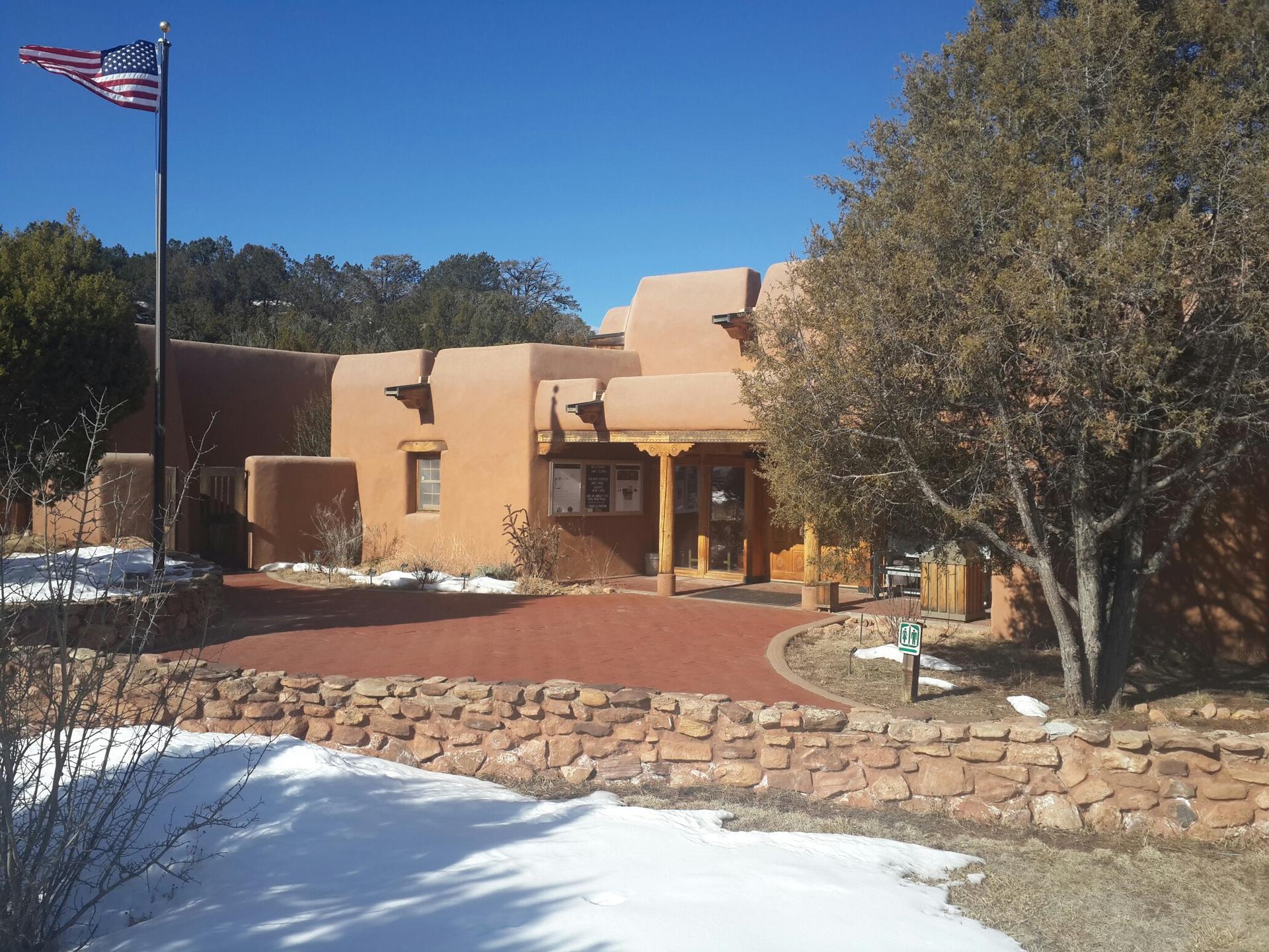 Adobe-style building with an American flag, surrounded by snow and trees.