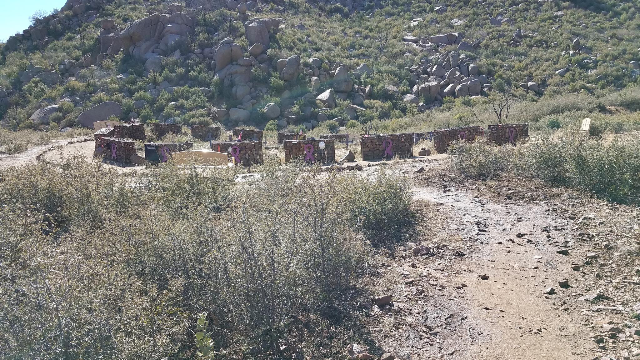 A dirt path leads to a circular stone structure on a rocky hillside.