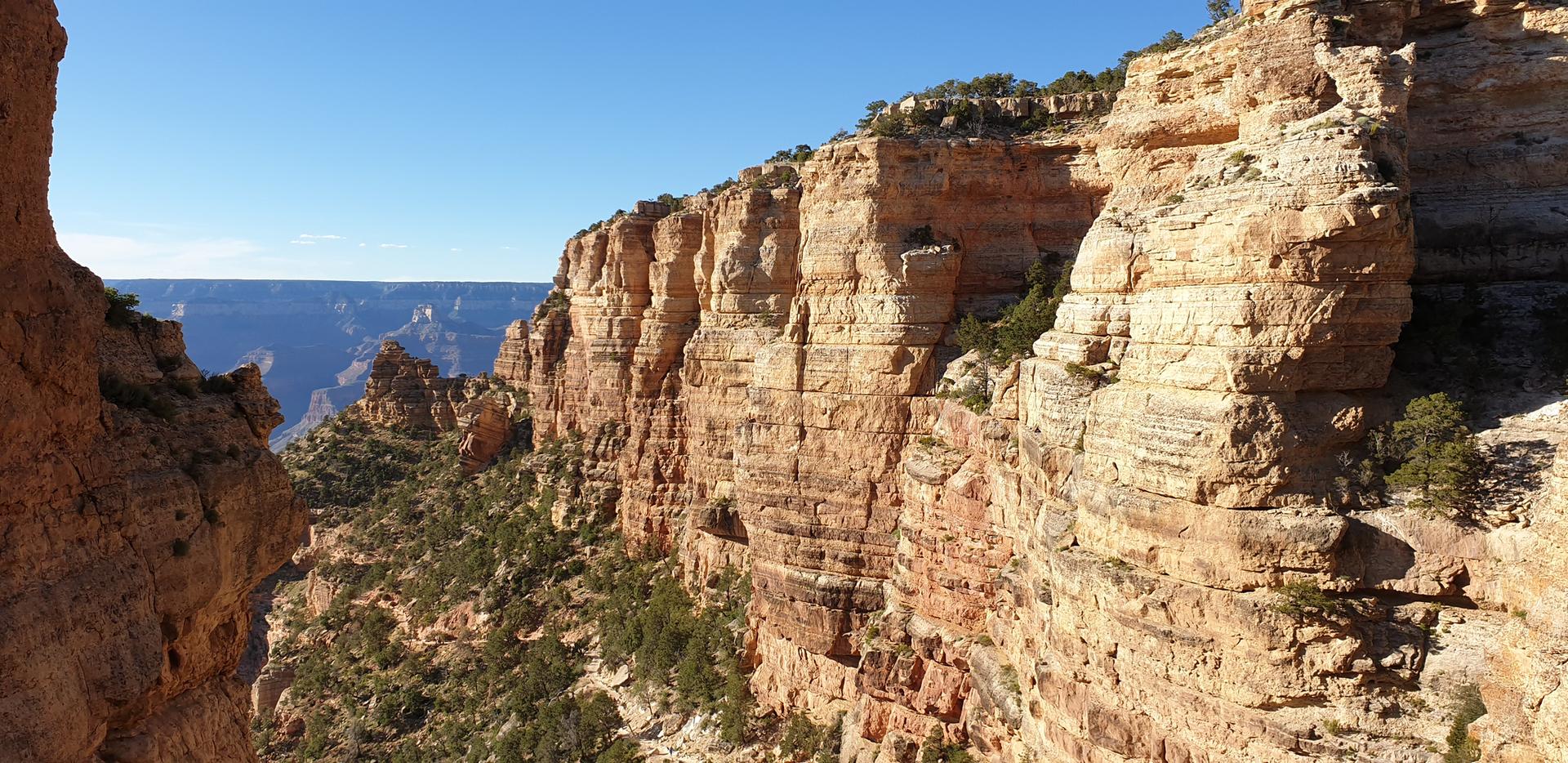 Steep, layered canyon walls under a clear blue sky.