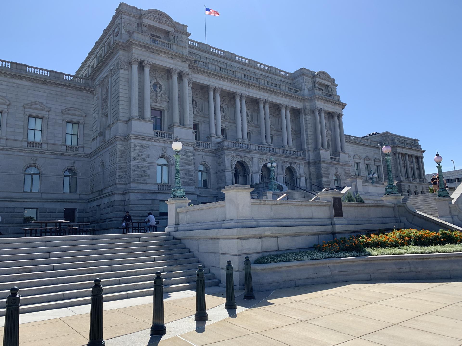 Large stone building with columns and grand staircase under clear sky.