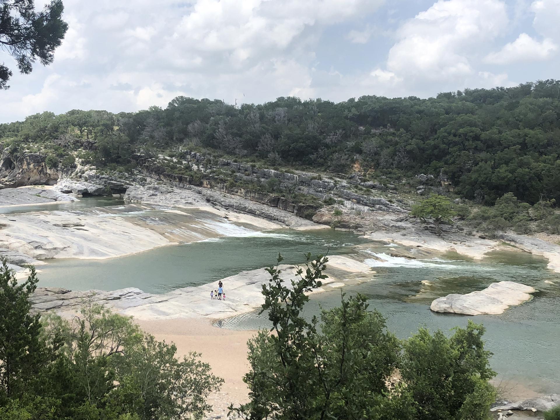 Overcast view of a river flowing over rocky ledges, with two people.