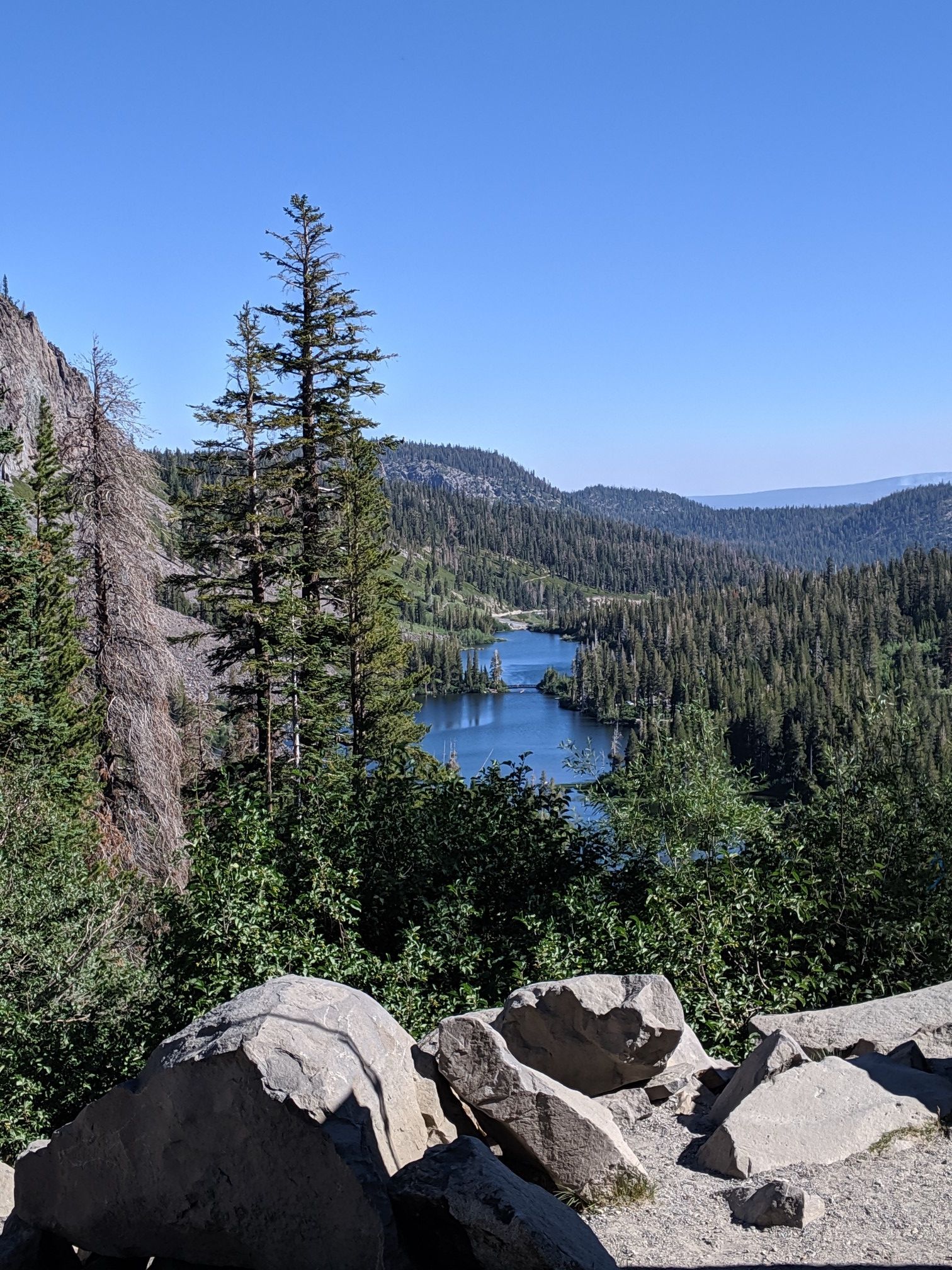 Scenic overlook of a blue lake winding through a forested valley. - Lakes Basin Path