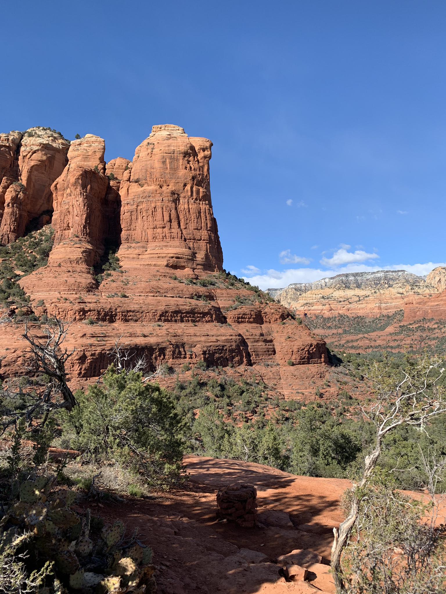 Towering red rock formation under a clear blue sky in a desert landscape.