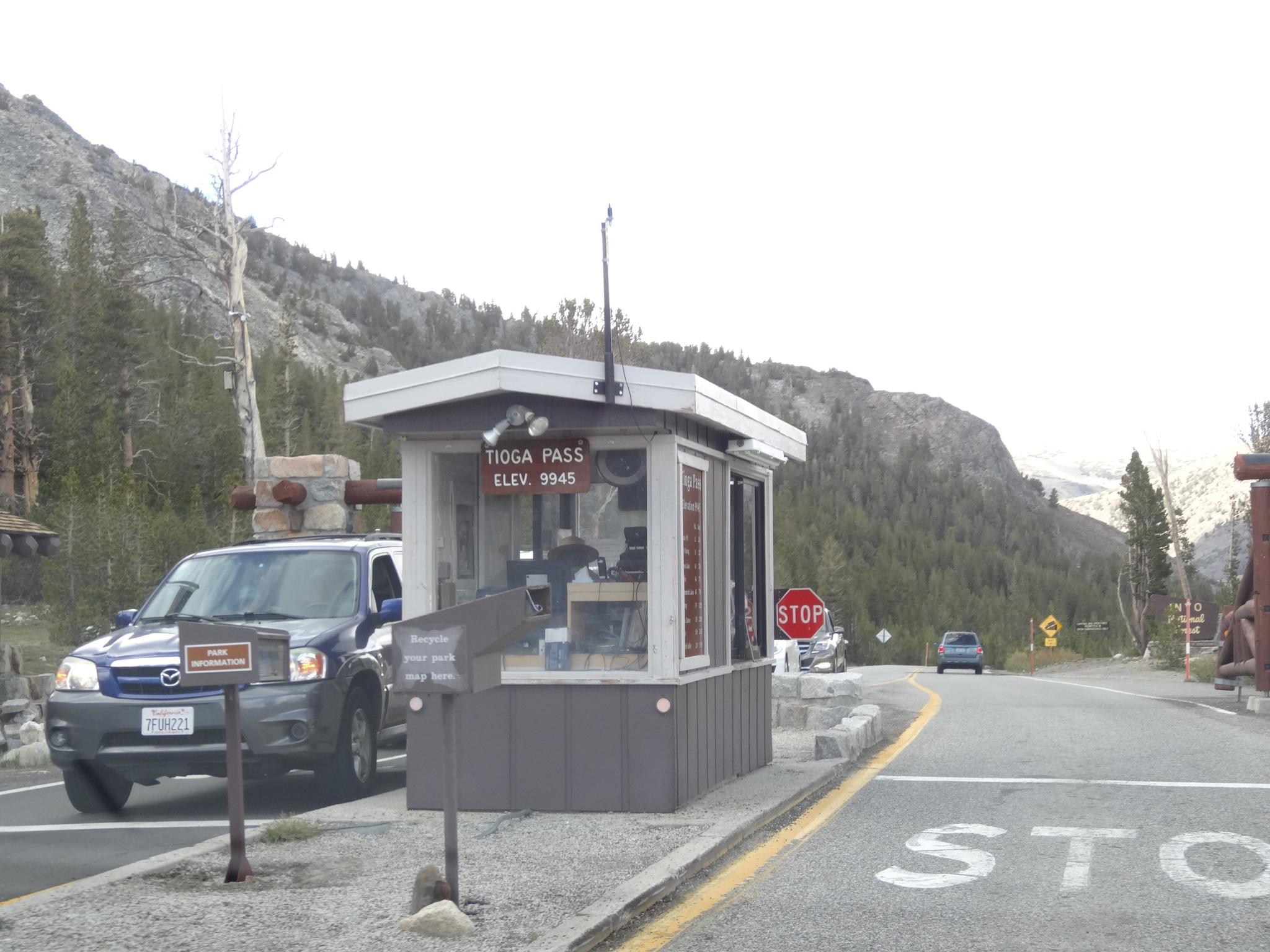 A car stopped at a roadside booth with a stop sign on an overcast day.
