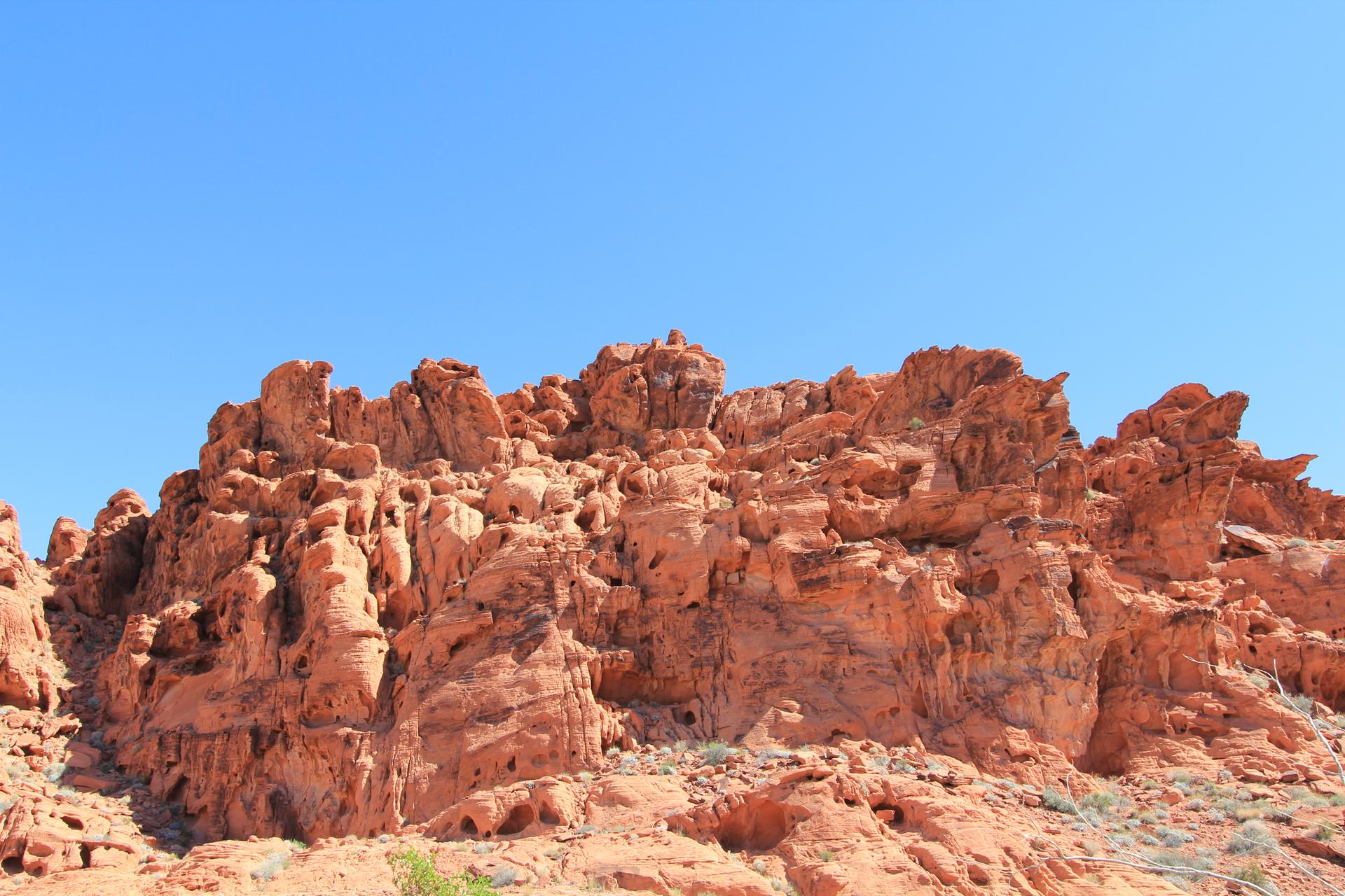 Jagged red rock formations under a clear, bright blue sky.