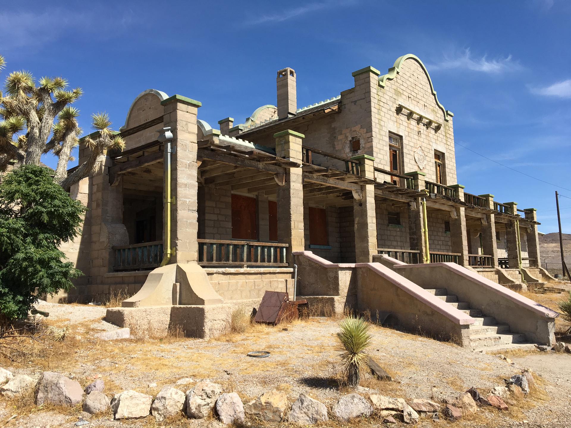 Ornate abandoned stone building with multiple porches and stairs in a desert.