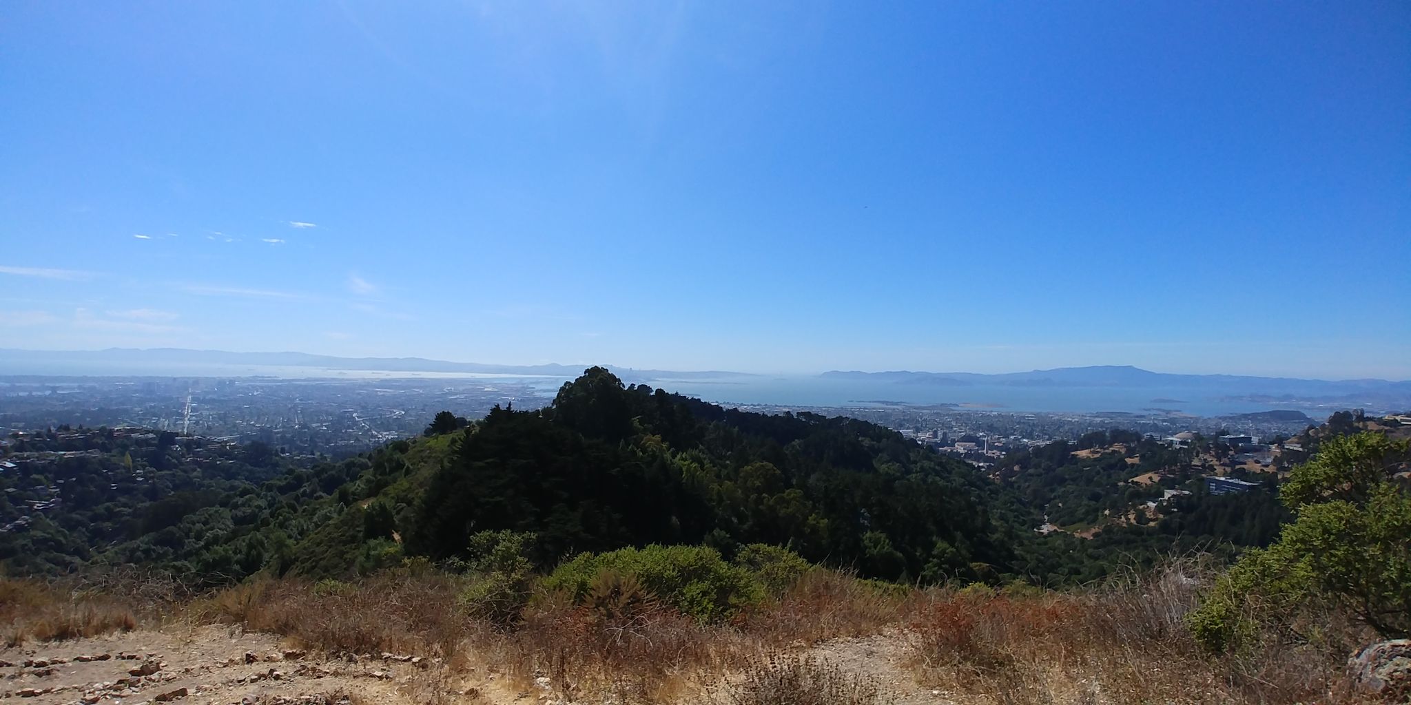 Sunny panoramic view of a city and bay from a dry, brushy hillside. - Chaparral Peak via Stonewall-Panoramic Trail