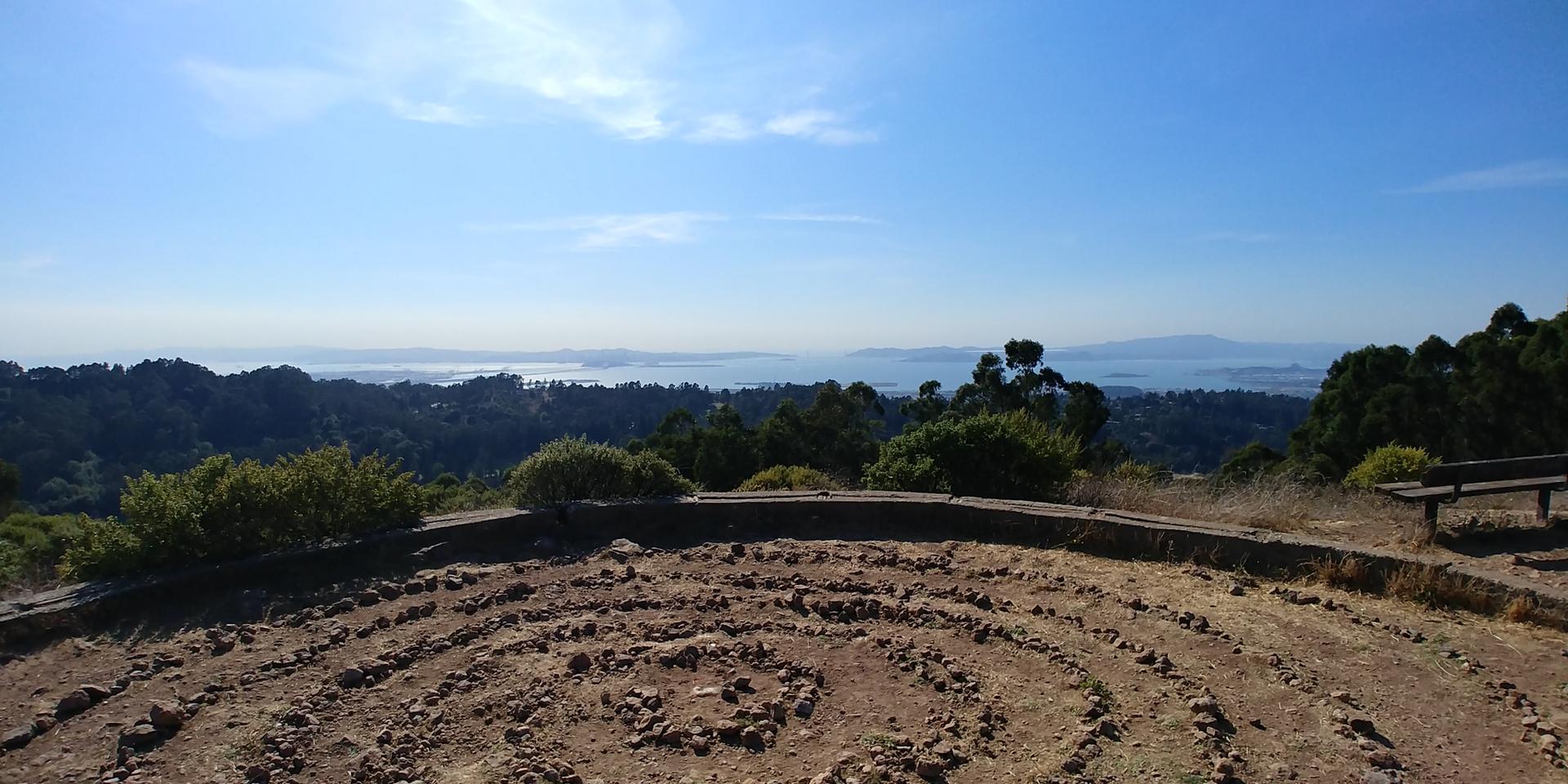 Rock labyrinth on a hill overlooking a distant body of water and horizon.