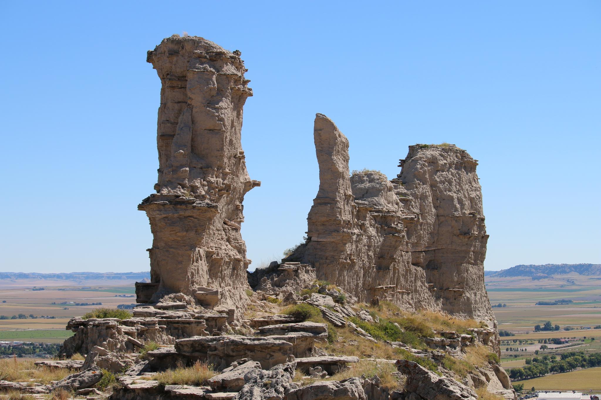 Two tall, weathered rock formations stand against a clear blue sky.