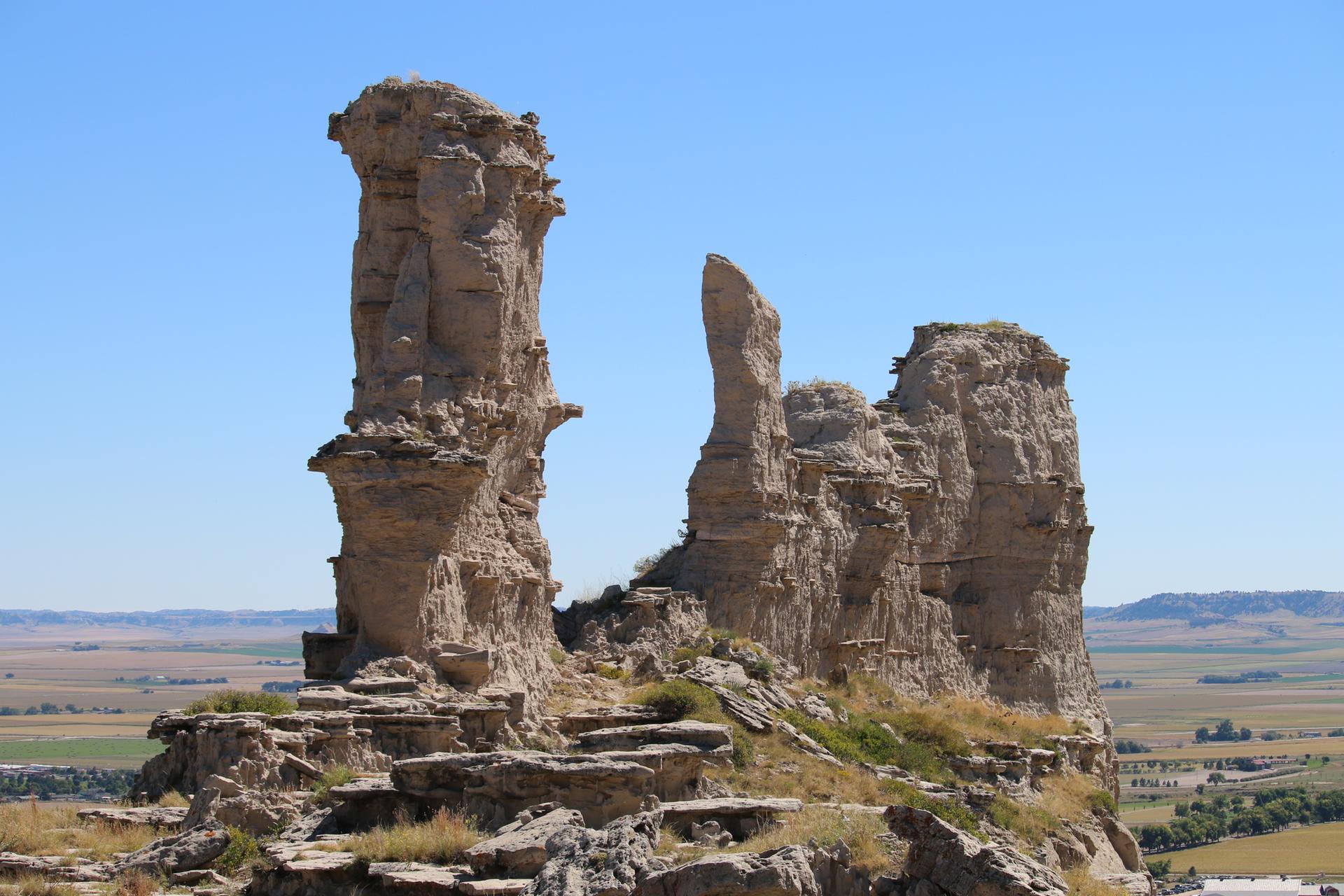 Two tall, weathered rock formations stand against a clear blue sky.