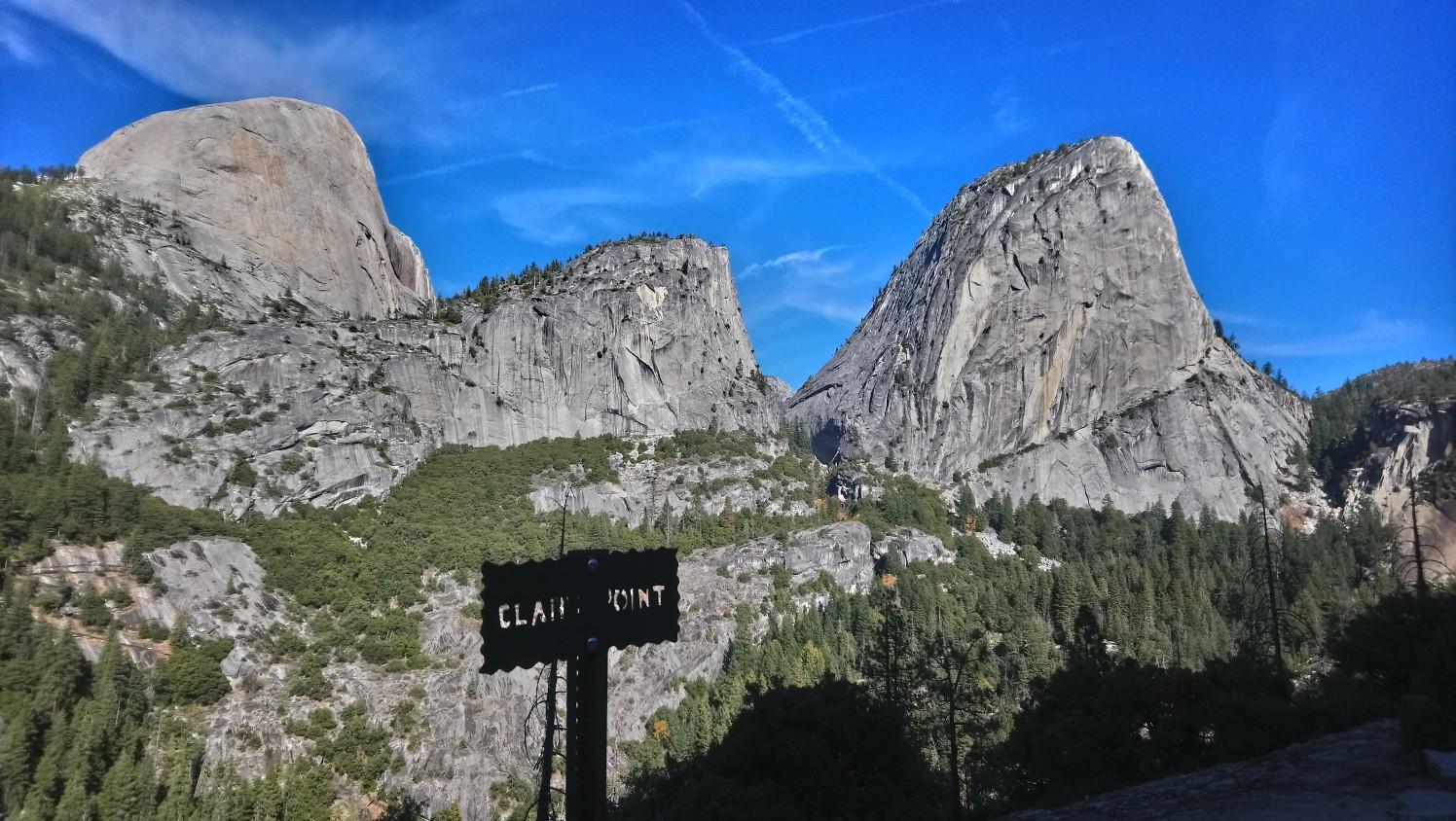 Two prominent granite mountains and a forest under a clear blue sky.