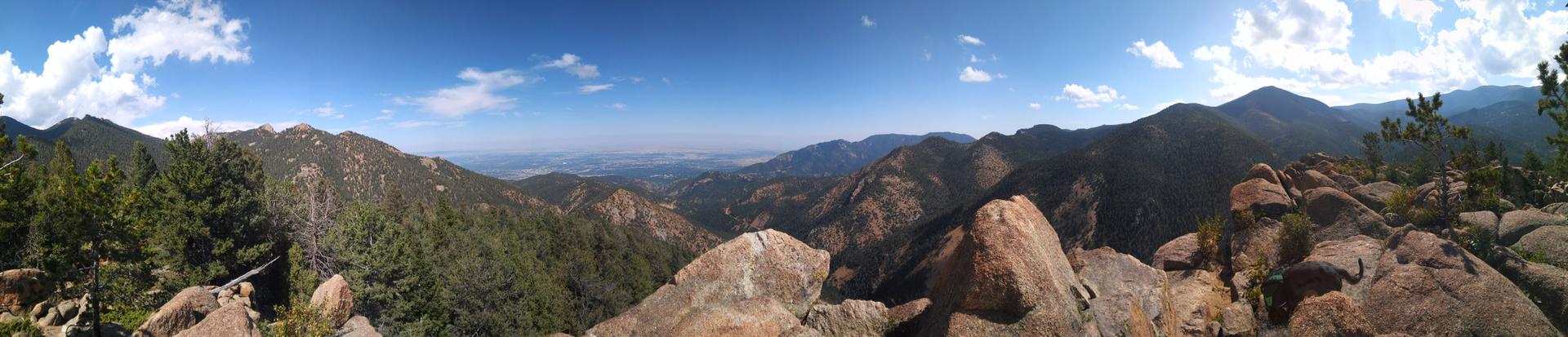 Panoramic view of vast green mountains and valleys under a blue sky.
