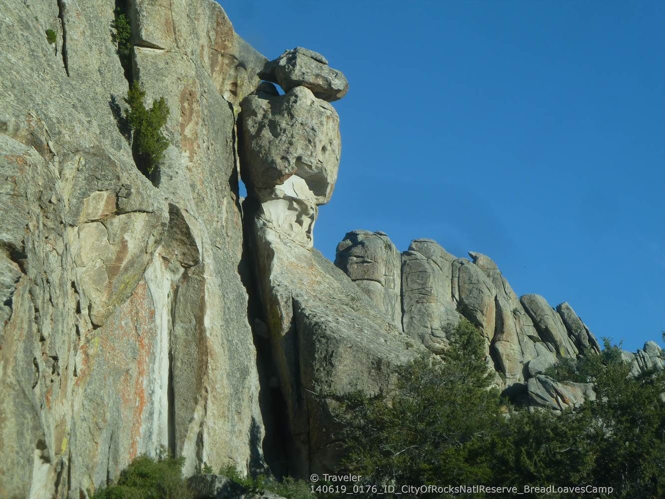Unique tall rock formation with a balanced rock against a clear blue sky. - City of Rocks Loop
