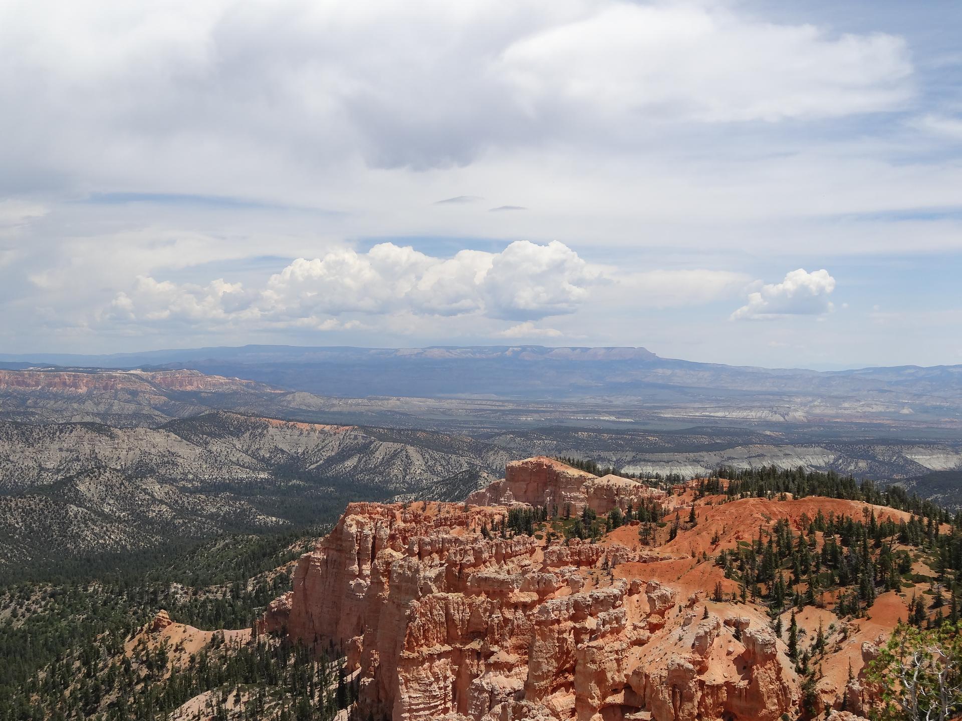 Vast canyon landscape with red rock formations and distant mountains.