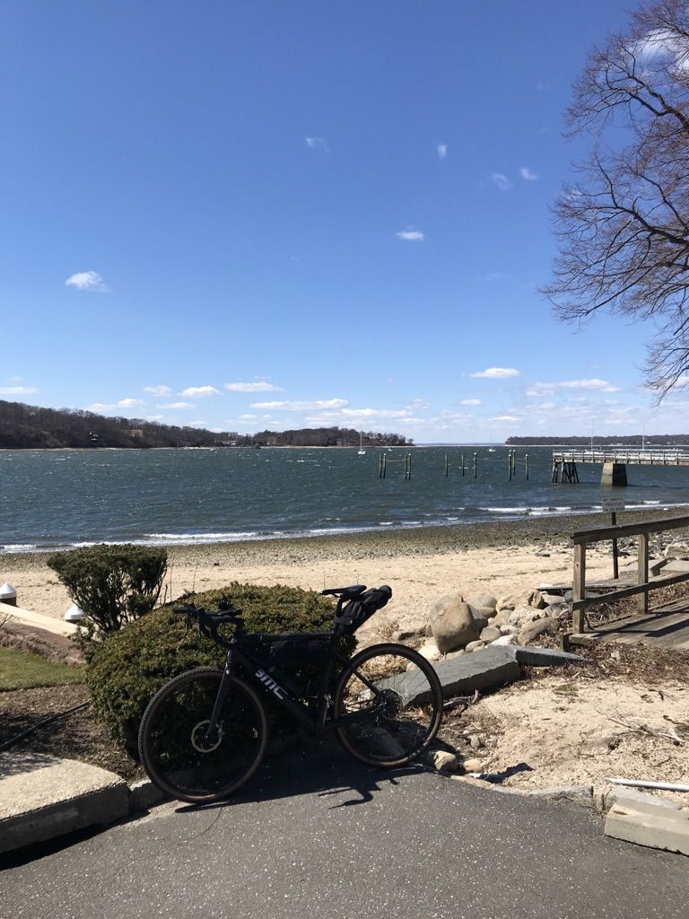 A bicycle parked on a sunny beach next to choppy water. - Asharoken Beach – Northport Harbor view loop from Huntington