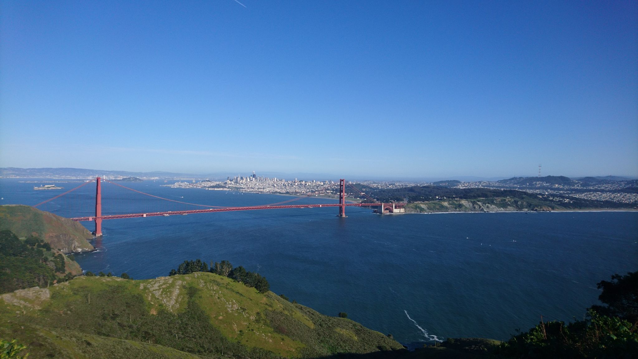 A large red suspension bridge spans blue water under a clear sky. - Marin Headlands and Bay Trail Loop