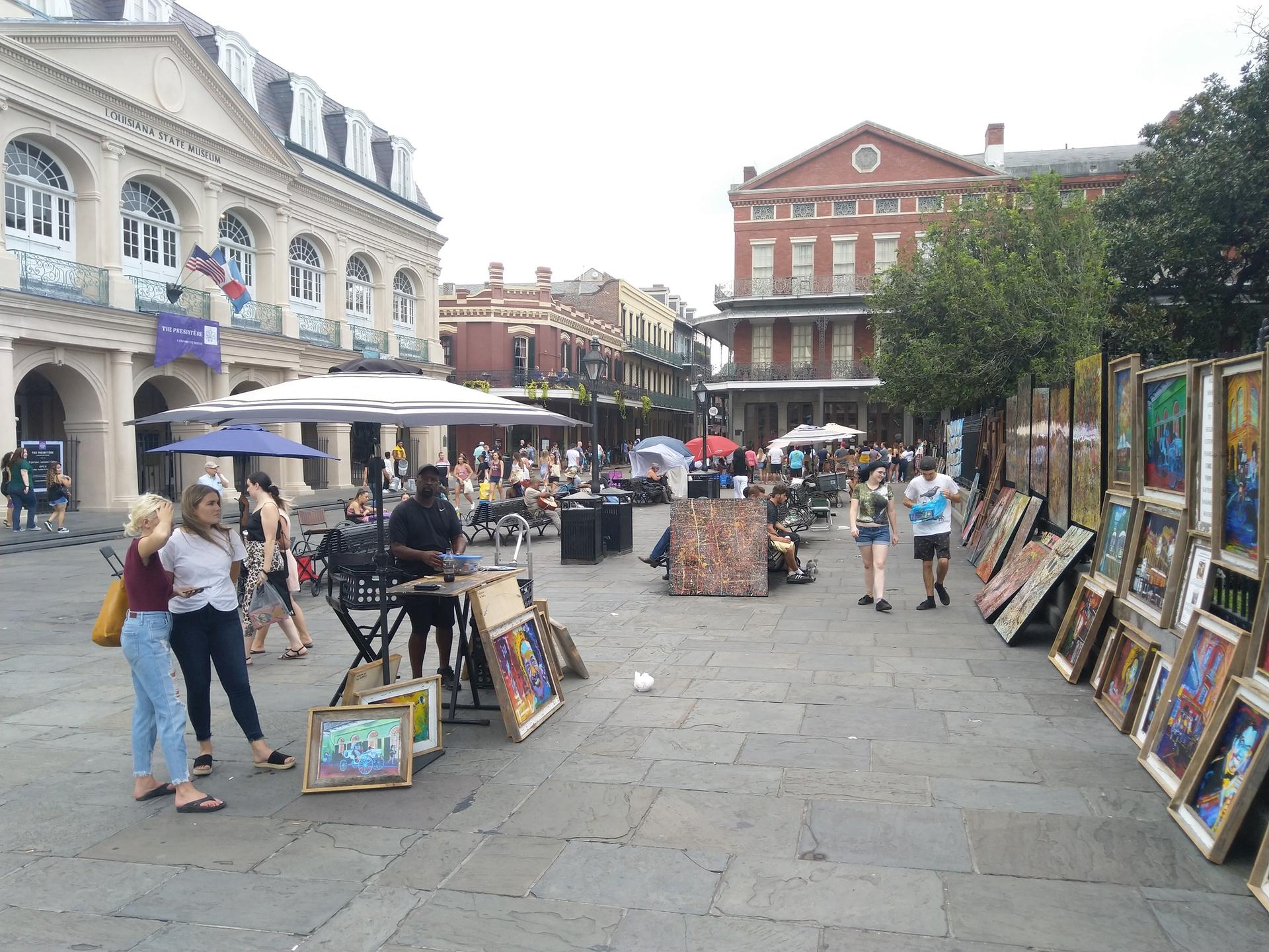A bustling outdoor market with people browsing art in a paved square.