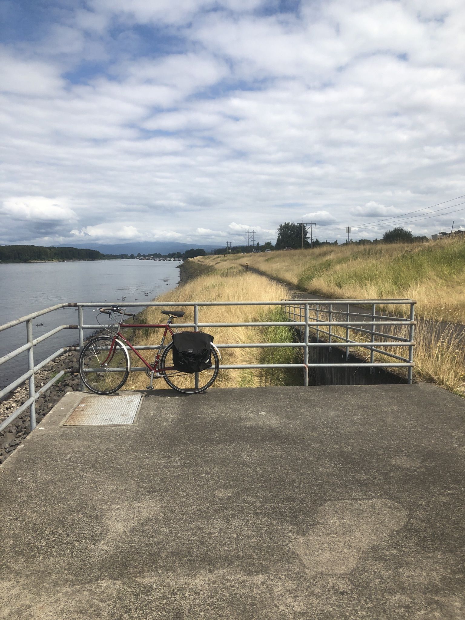 A bicycle rests on a concrete platform overlooking a wide river. - Marine Drive Trail Loop
