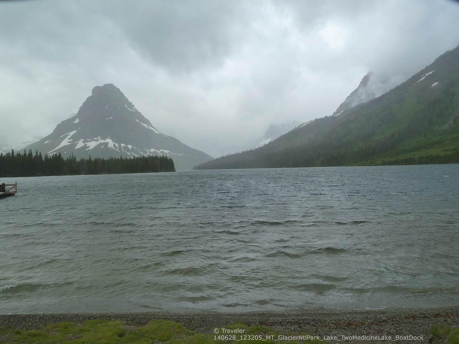 A wide lake under a cloudy sky, with distant mountains shrouded in mist.