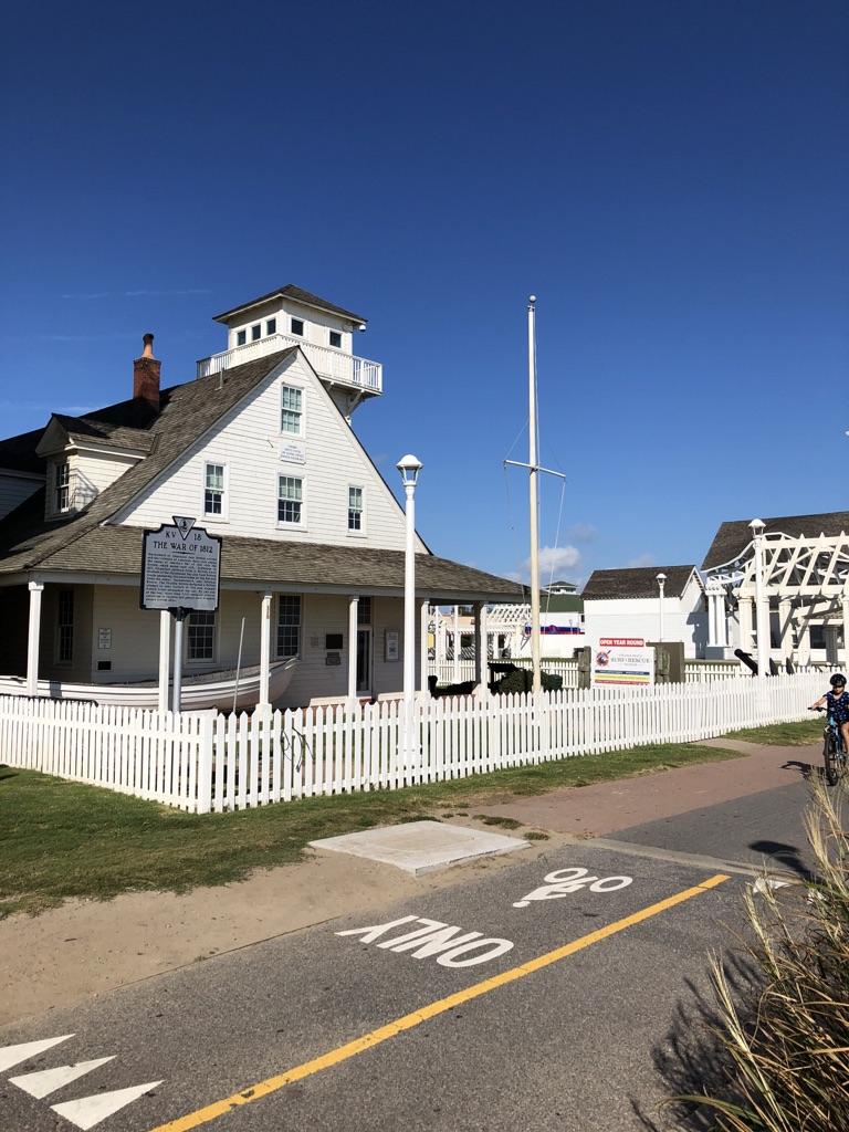 White historic building with a tower and picket fence on a sunny day.