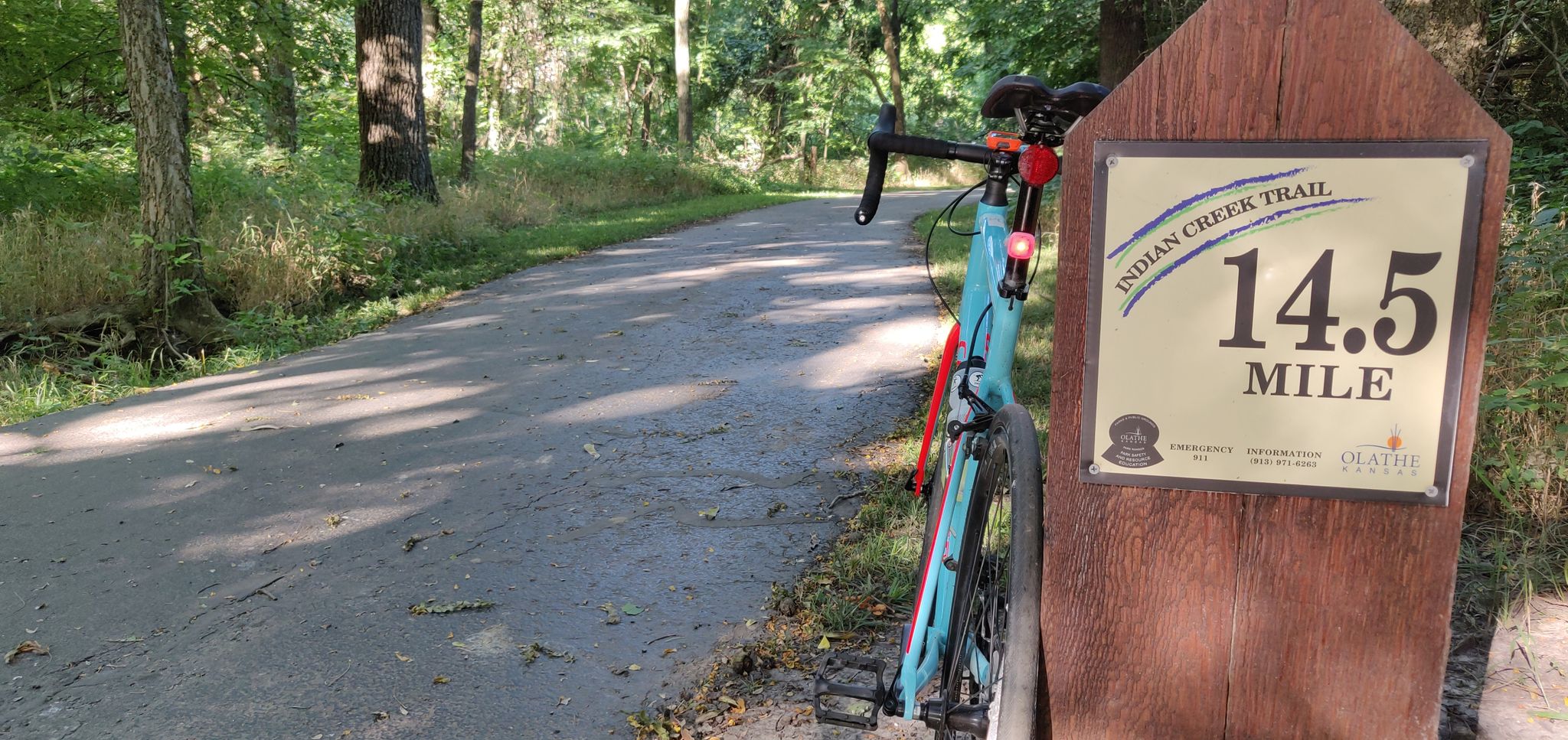 Bicycle leaning against a mile marker on a sunny paved forest path. - Indian Creek Trail – Amesbury Lake Park loop from South OP Express 569