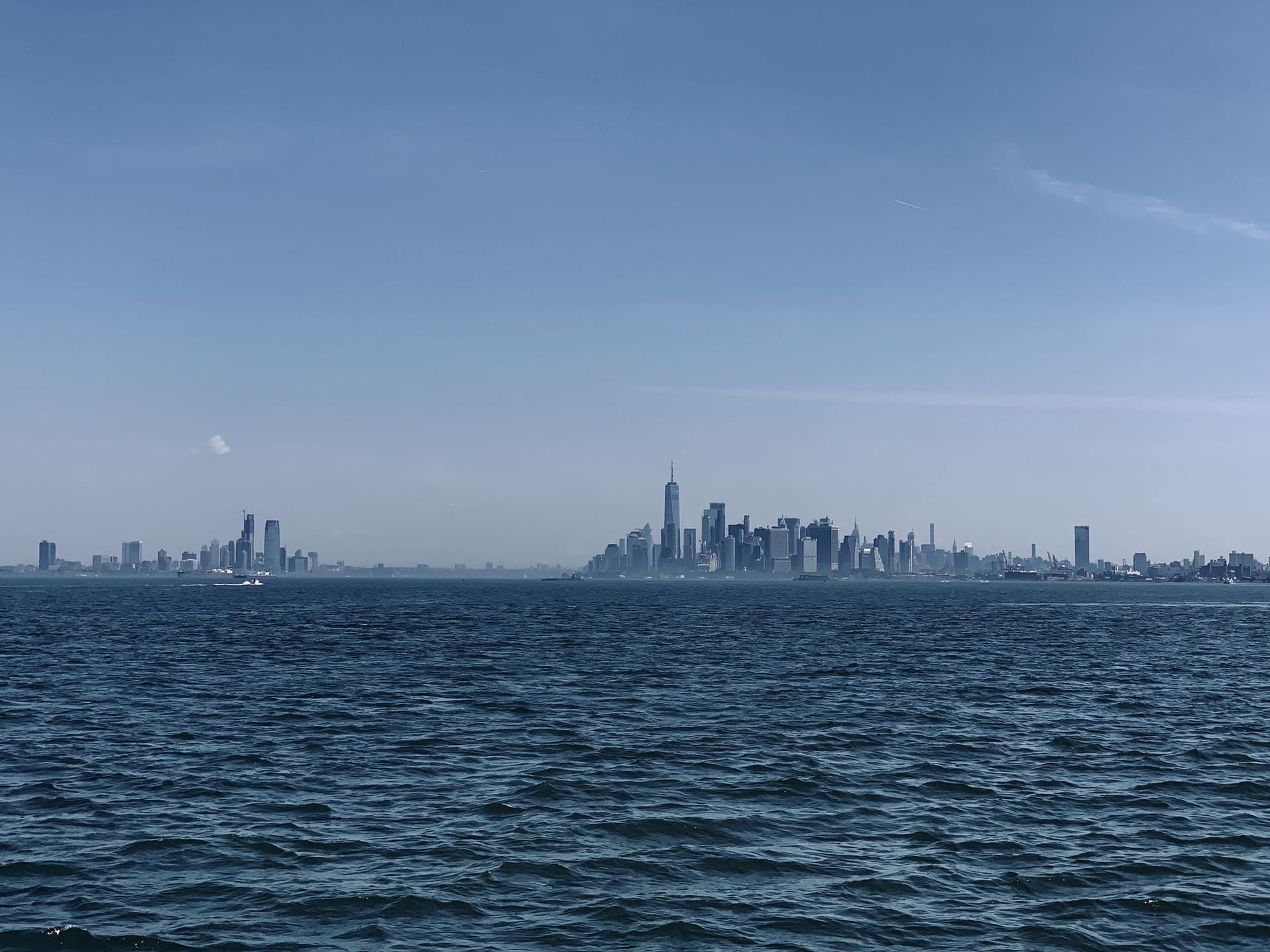 A distant city skyline rises above a wide expanse of blue water.