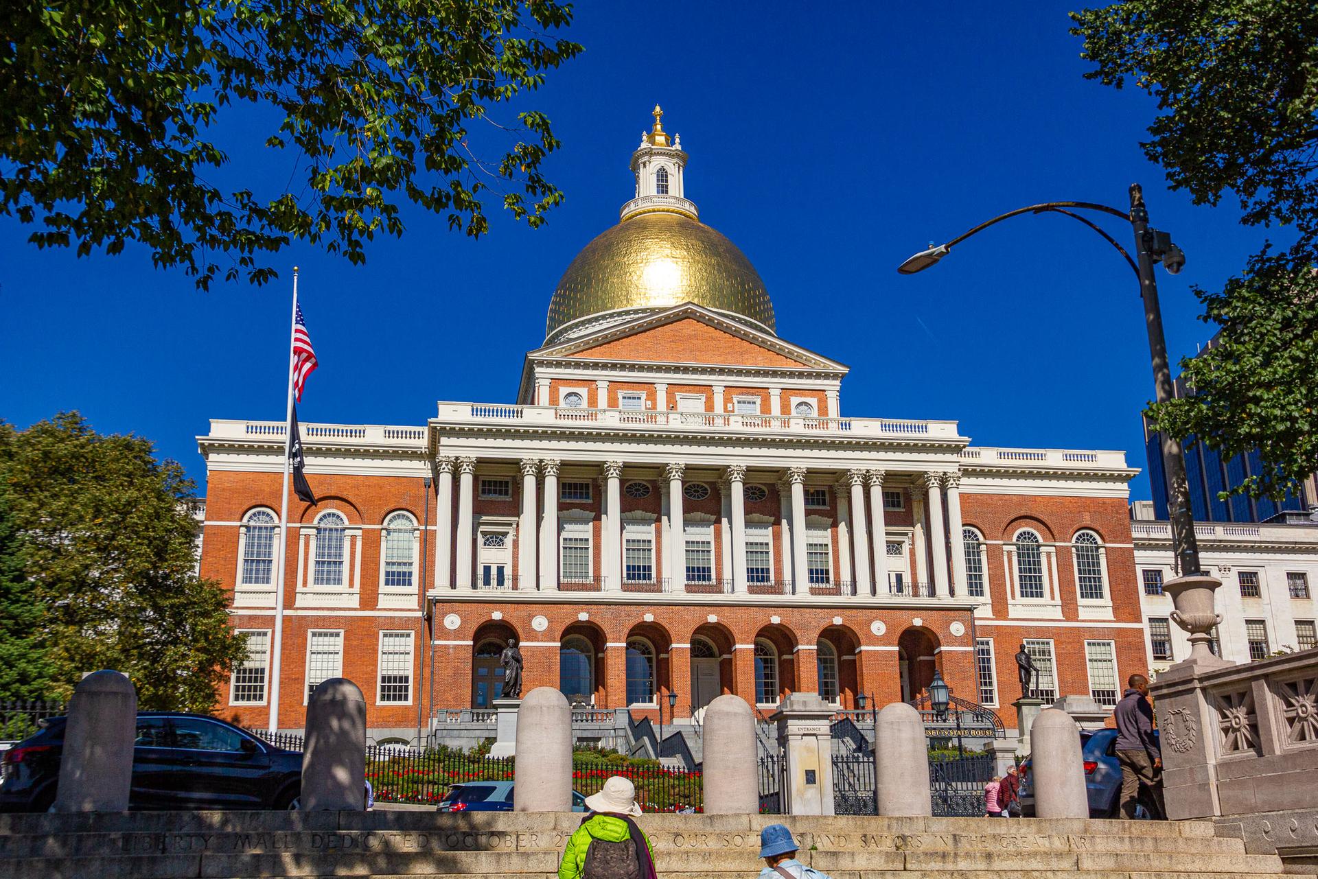 Grand building with a golden dome and columns under a bright blue sky.