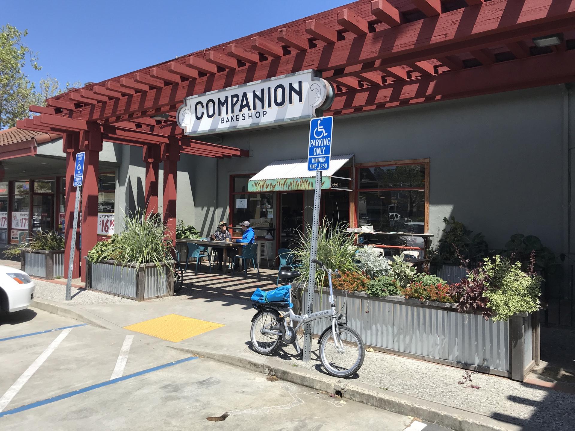 Exterior of a bakeshop with outdoor seating and a parked bicycle.